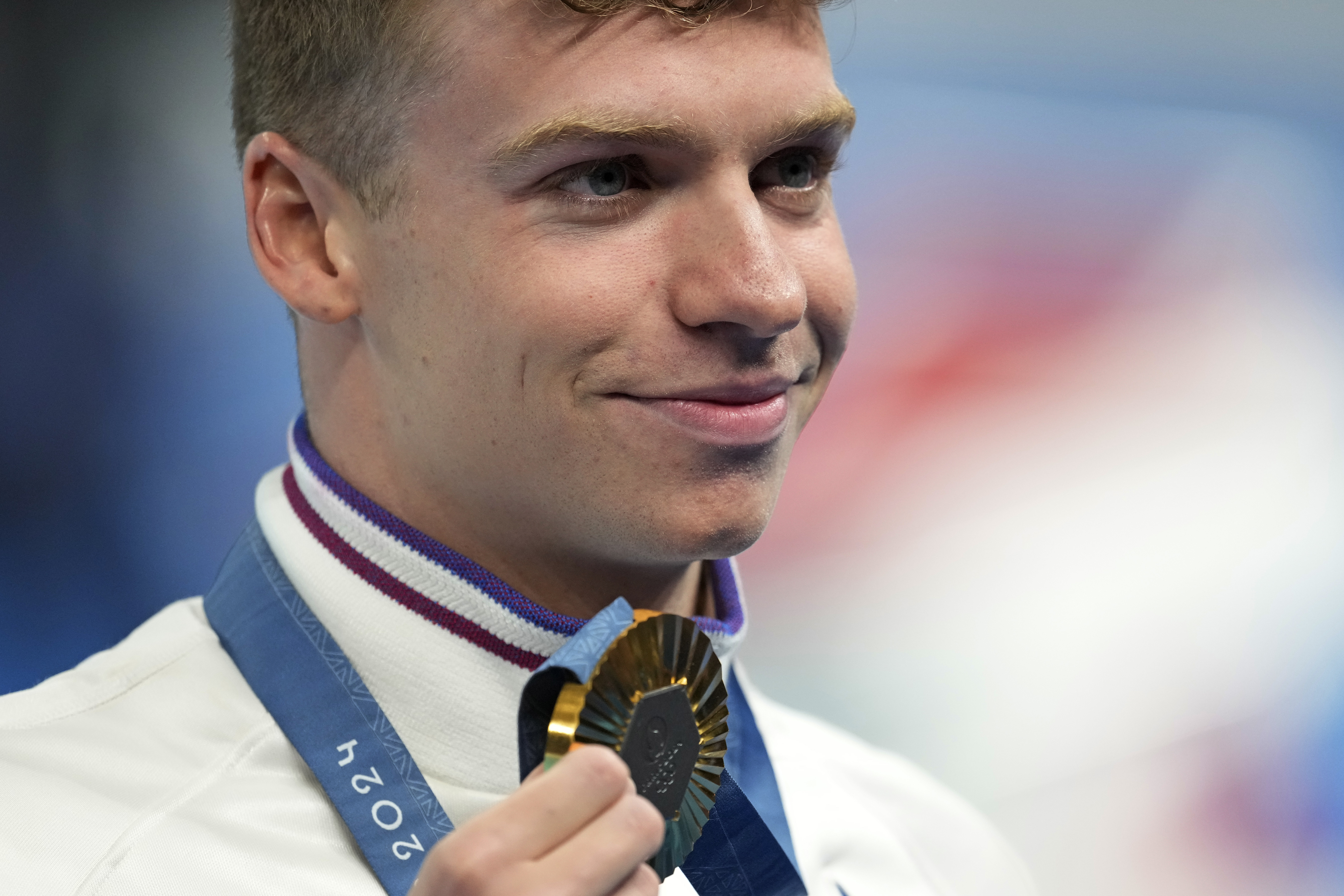Leon Marchand of France, poses with his gold medal for the men's 200-meter individual medley final at the 2024 Summer Olympics, Friday, Aug. 2, 2024, in Nanterre, France.