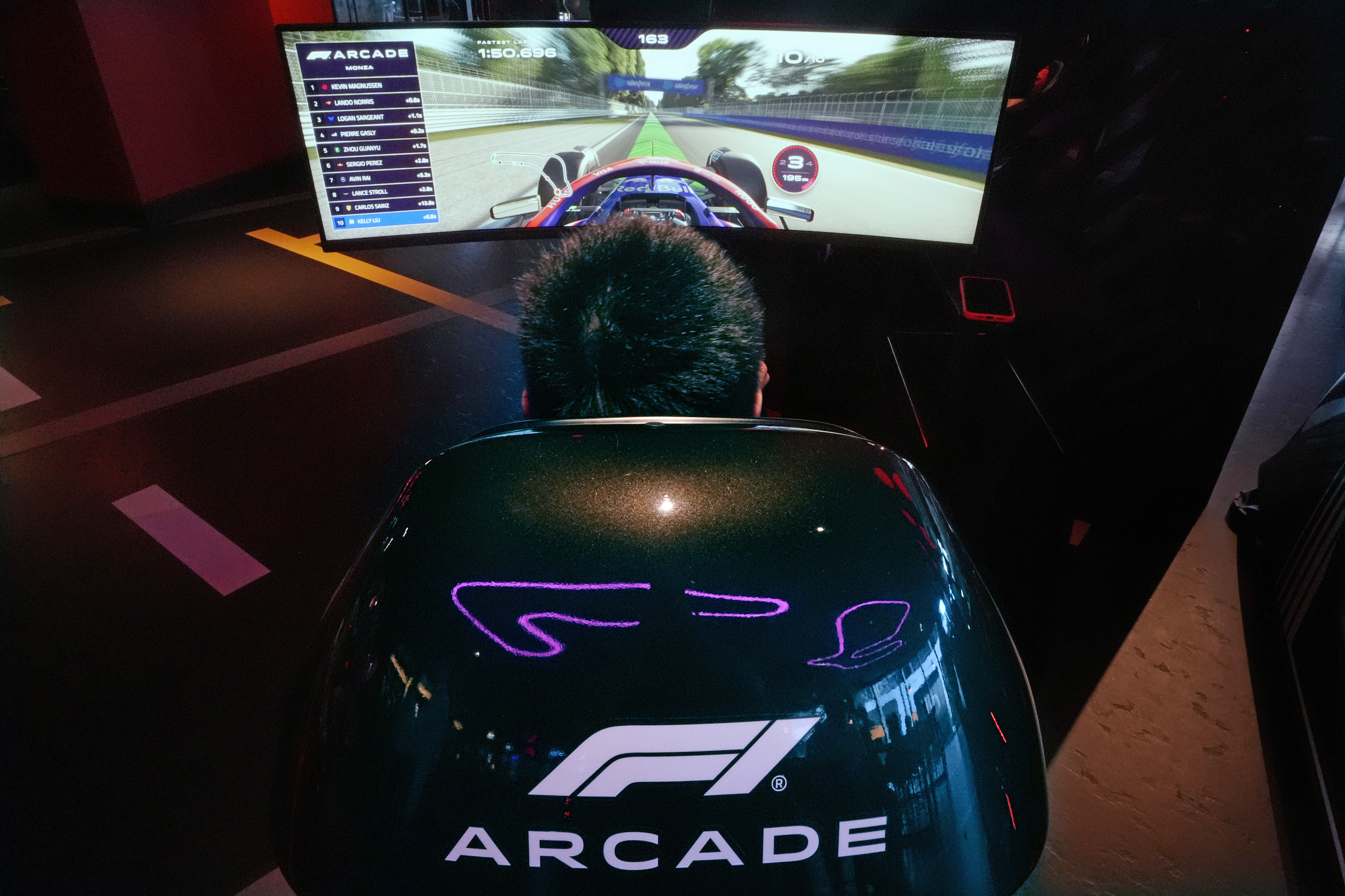 A video game driver races on a simulated track at the F1 Boston Arcade, Monday, July 8, 2024, in Boston. 