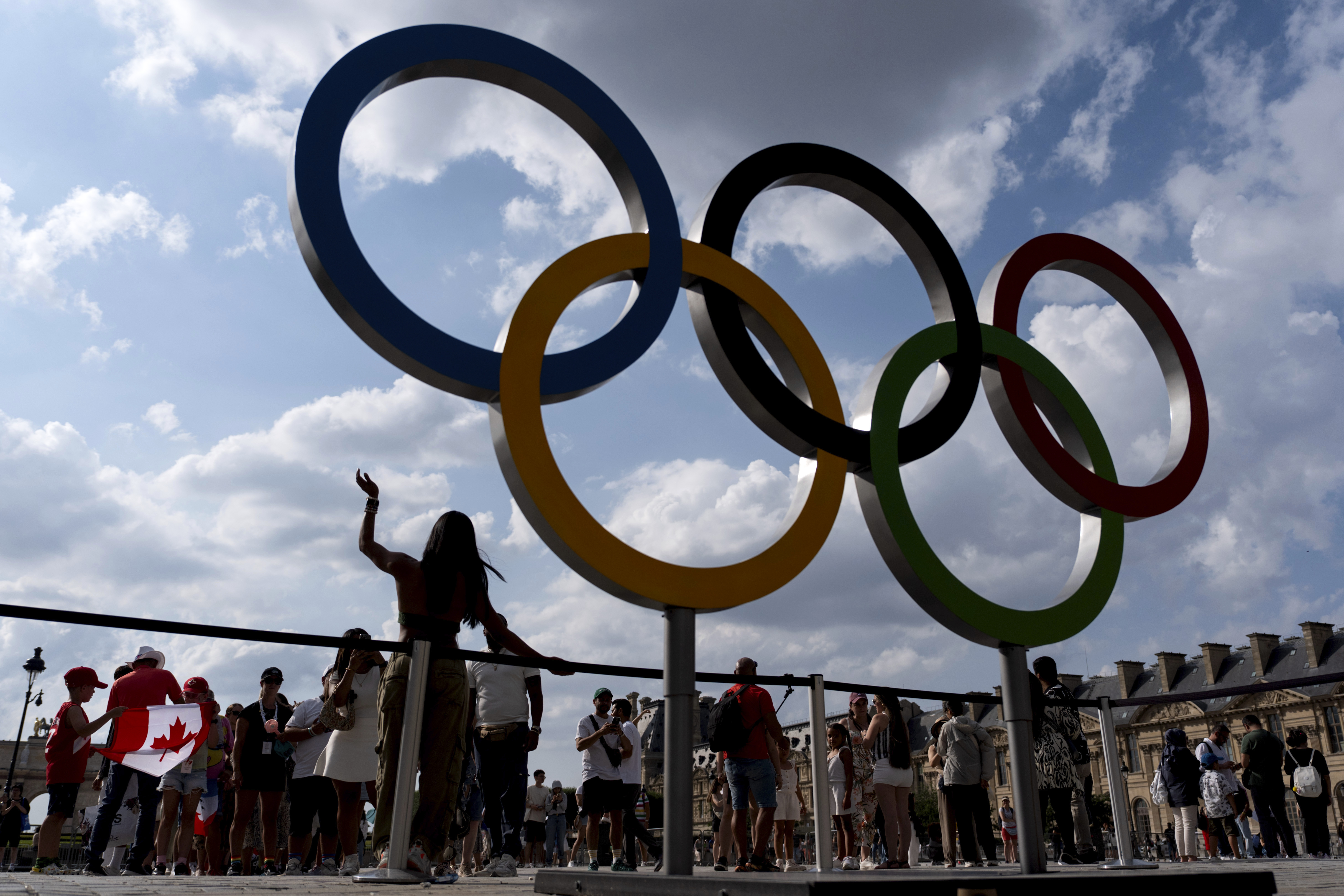 The public lines up to have their picture taken with the Olympic rings in front of the Louvre museum at the 2024 Summer Olympics, Thursday, Aug. 1, 2024, in Paris, France.