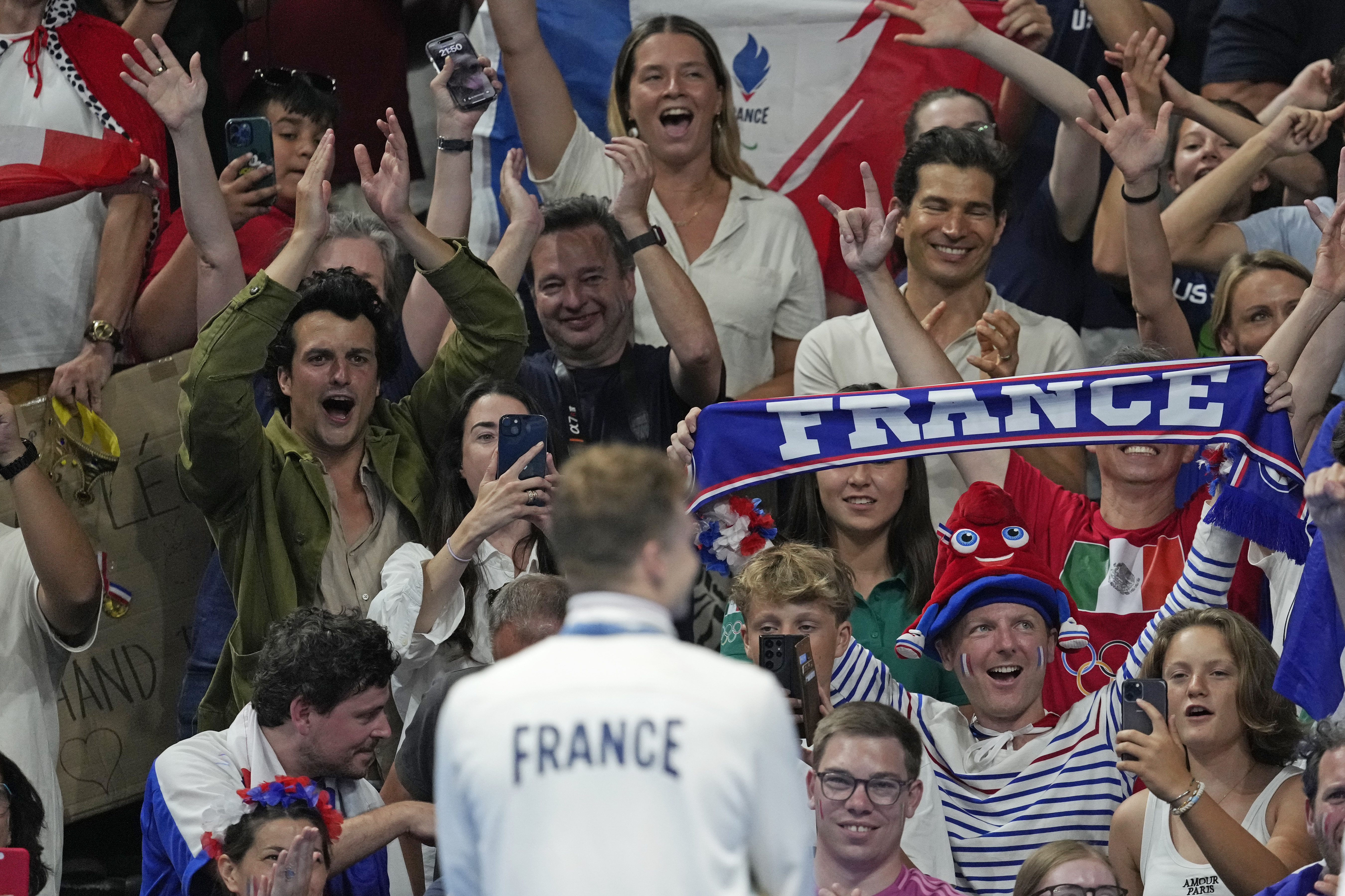 Leon Marchand of France, reacts as he stands on the podium to look at his supporters after receiving his gold medal for the men's 200-meter individual medley final at the 2024 Summer Olympics, Friday, Aug. 2, 2024, in Nanterre, France. 