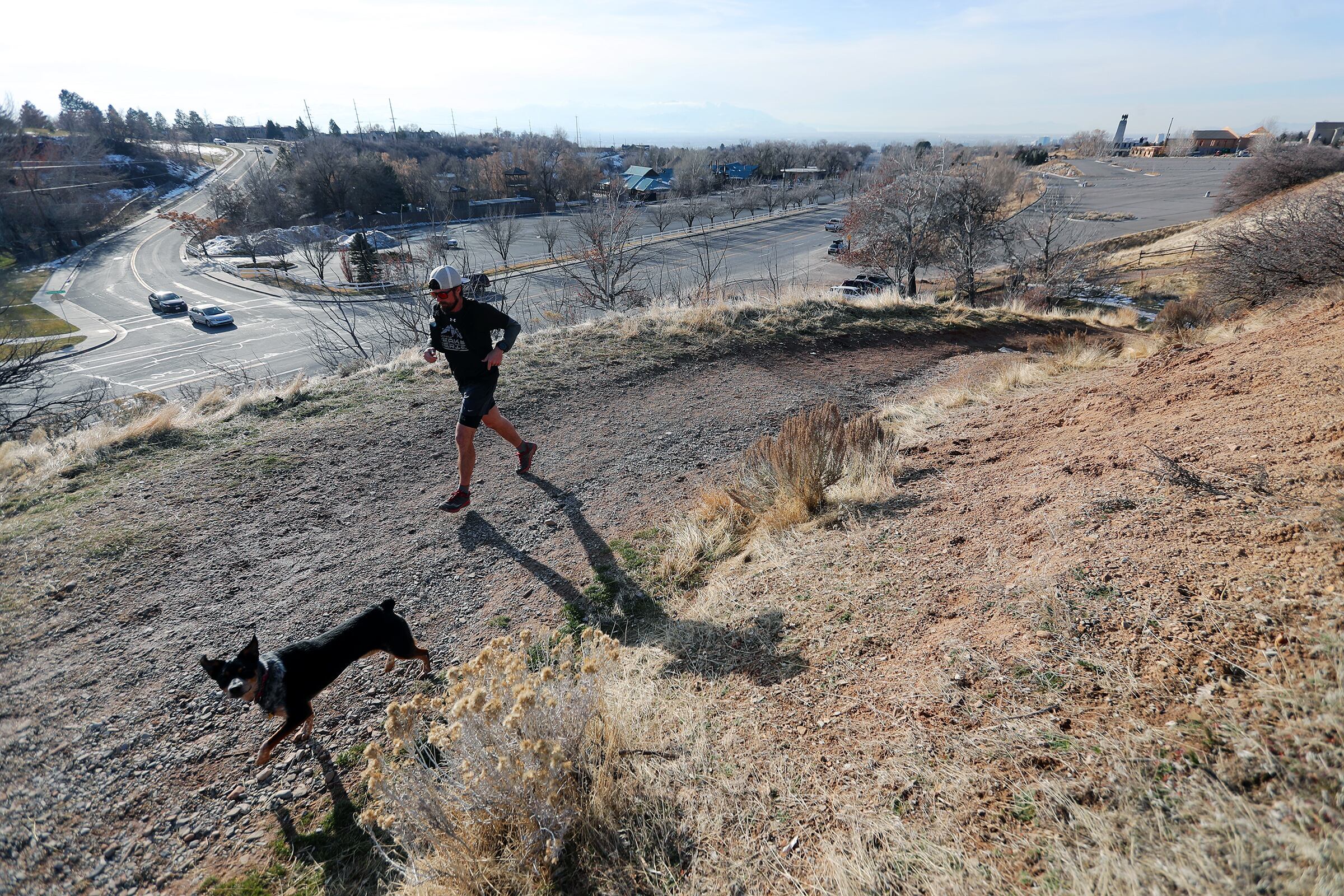 A jogger and his dog run on the trails above This Is the Place Heritage State Park in Salt Lake City on Dec. 10, 2019. Giving your dog opportunities to safely practice predatory behaviors can help you get them under control, research suggests.
