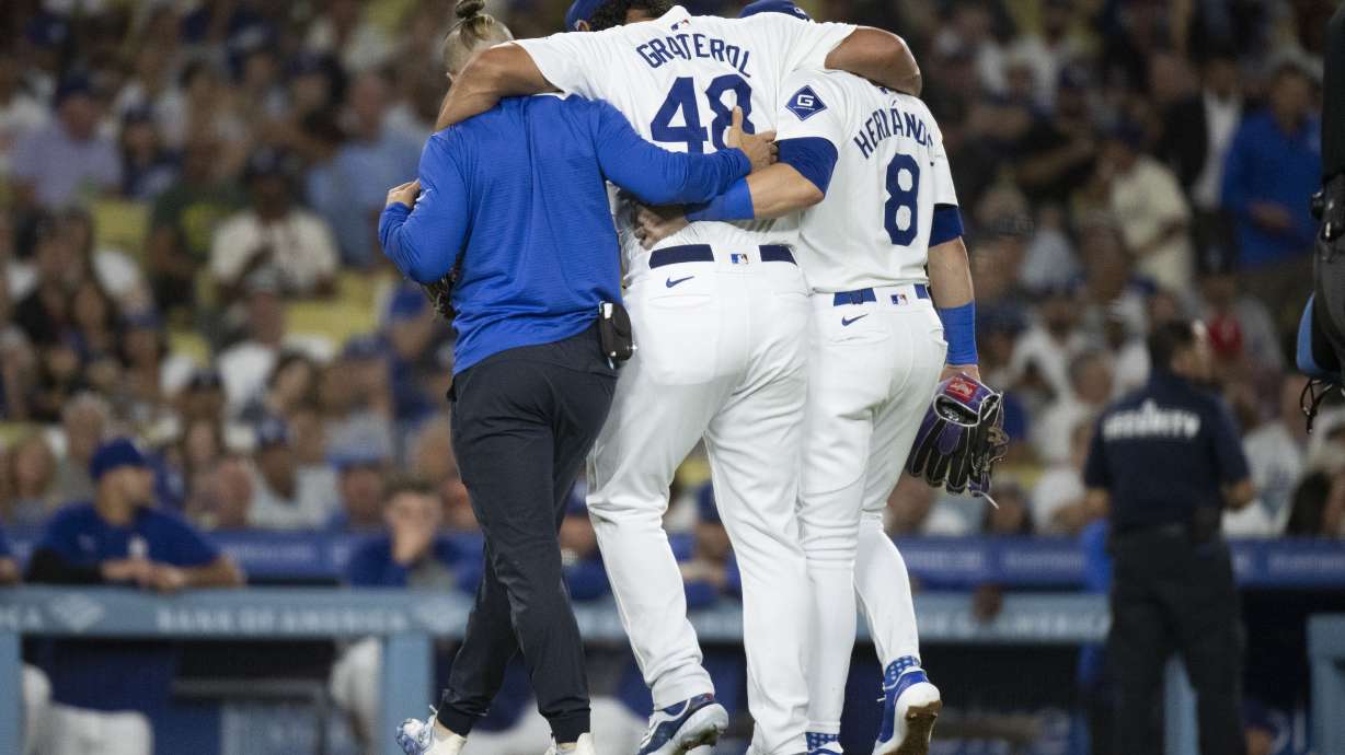 Los Angeles Dodgers relief pitcher Brusdar Graterol (48) is helped getting out of a baseball game against the Philadelphia Phillies due to an apparent injury in Los Angeles, Tuesday, Aug. 6, 2024.