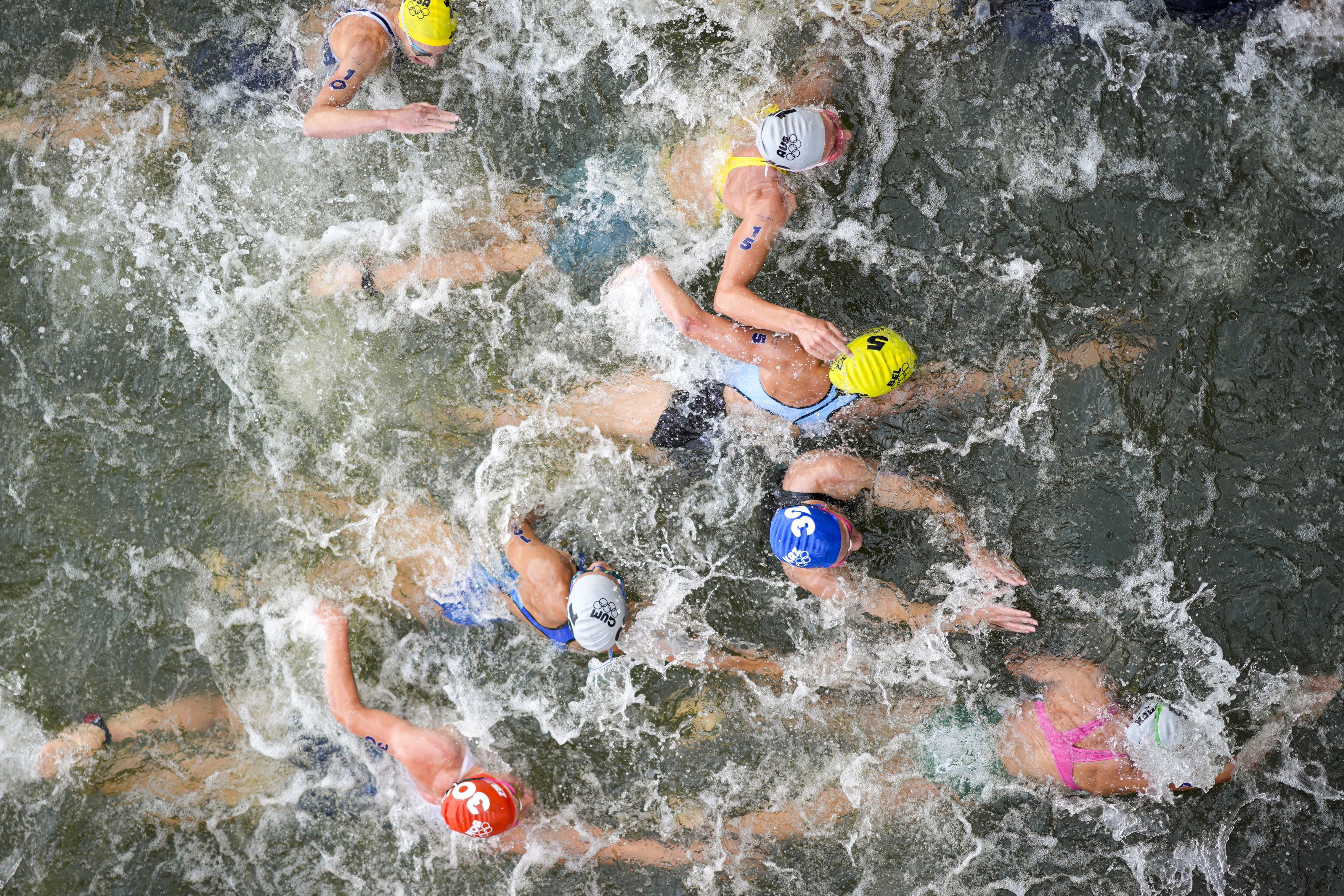 FILE - Australia's Natalie Van Coevorden (15), Belgium's Claire Michel (5) and Ekaterina Shabalina, of Kazakhstan (32) compete in the swim leg of the women's individual triathlon competition at the 2024 Summer Olympics, Wednesday, July 31, 2024, in Paris, France. Belgium's Olympic committee announced Sunday Aug.4, 2024 that it would withdraw its team from the mixed relay triathlon at the Paris Olympics after one of its competitors who swam in the Seine River fell ill. Claire Michel, who competed in the women's triathlon Wednesday, "is unfortunately ill and will have to withdraw from the competition," the Belgian Olympic and Interfederal Committee said in a statement. 
