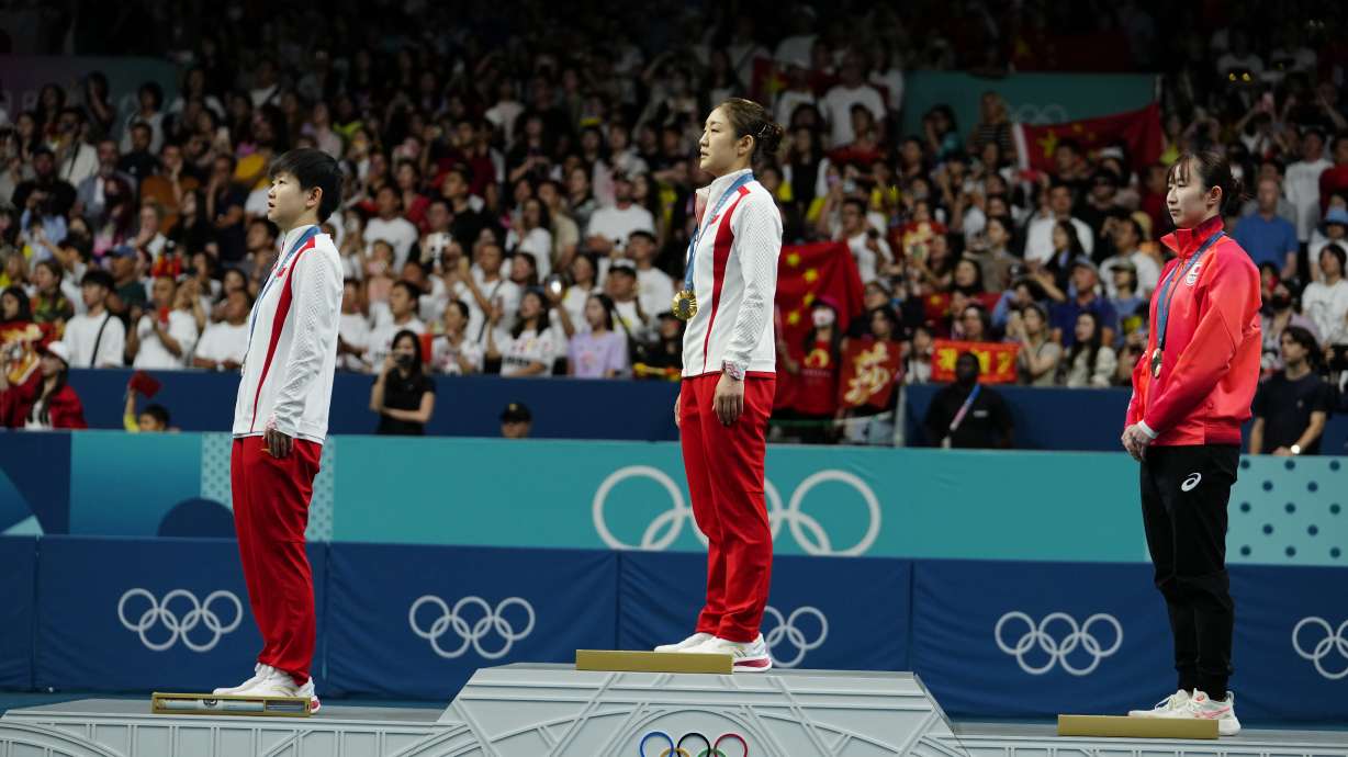 Gold medalist China's Chen Meng, center, silver medalist China's Sun Yingsha, left, and bronze medalist Japan's Hina Hayata stand for the Chinese national anthem during the medal ceremony of the women's singles table tennis at the 2024 Summer Olympics, Saturday, Aug. 3, 2024, in Paris, France.