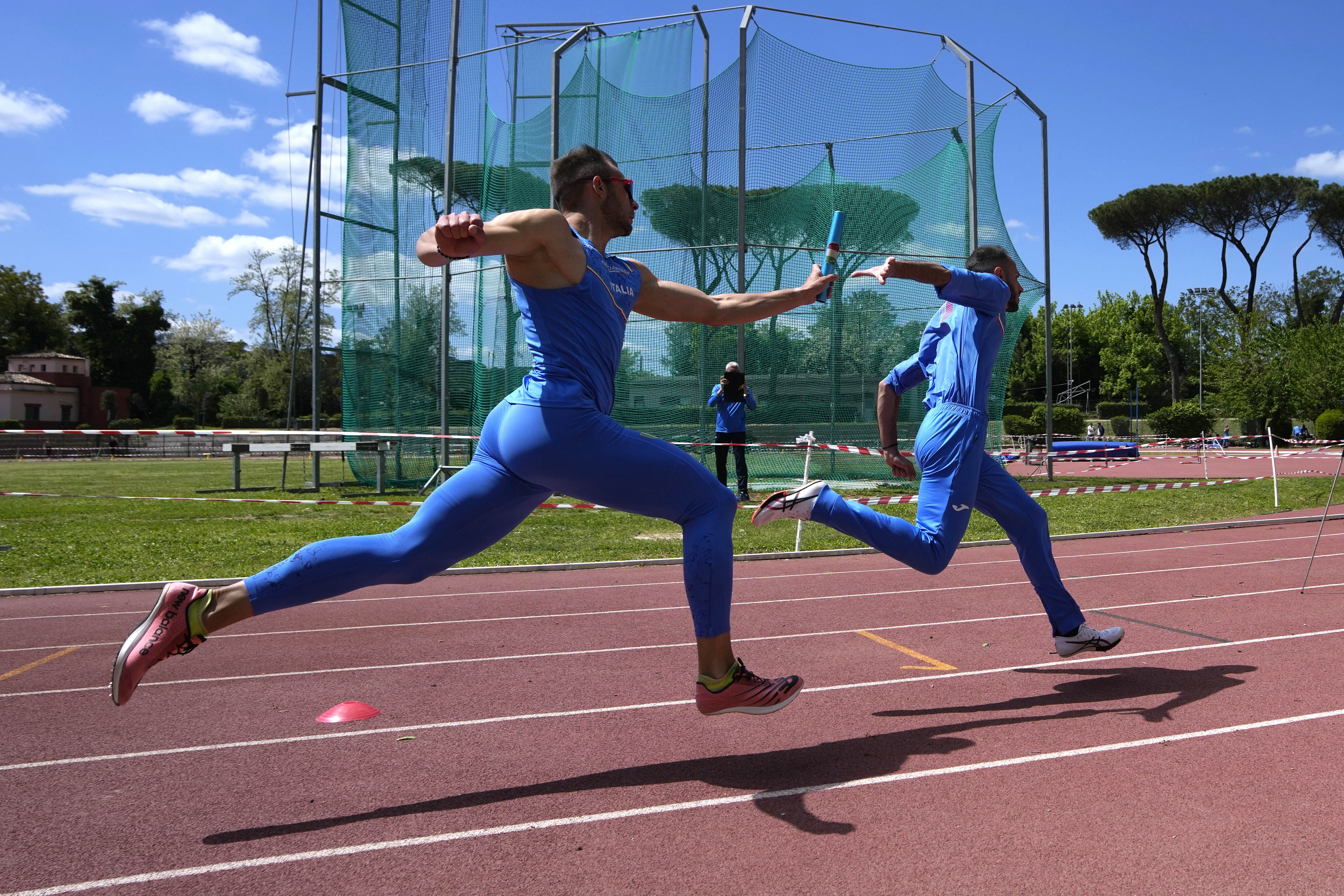 Italian coach Filippo Di Mulo films a baton exchange between Marco Ricci, left, and Lorenzo Patta during a training session in Rome, Friday, April 19, 2024. 