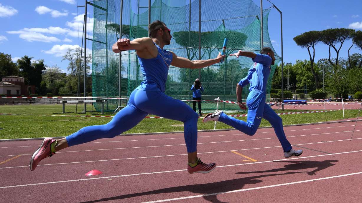 Italian coach Filippo Di Mulo films a baton exchange between Marco Ricci, left, and Lorenzo Patta during a training session in Rome, Friday, April 19, 2024.