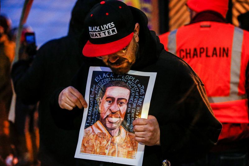 A man holds an image of George Floyd at a vigil on the second anniversary of the death of Floyd, a black man who was killed in 2020 by white police officer Derek Chauvin by kneeling on his neck, in Minneapolis, Minn., May 25, 2022.