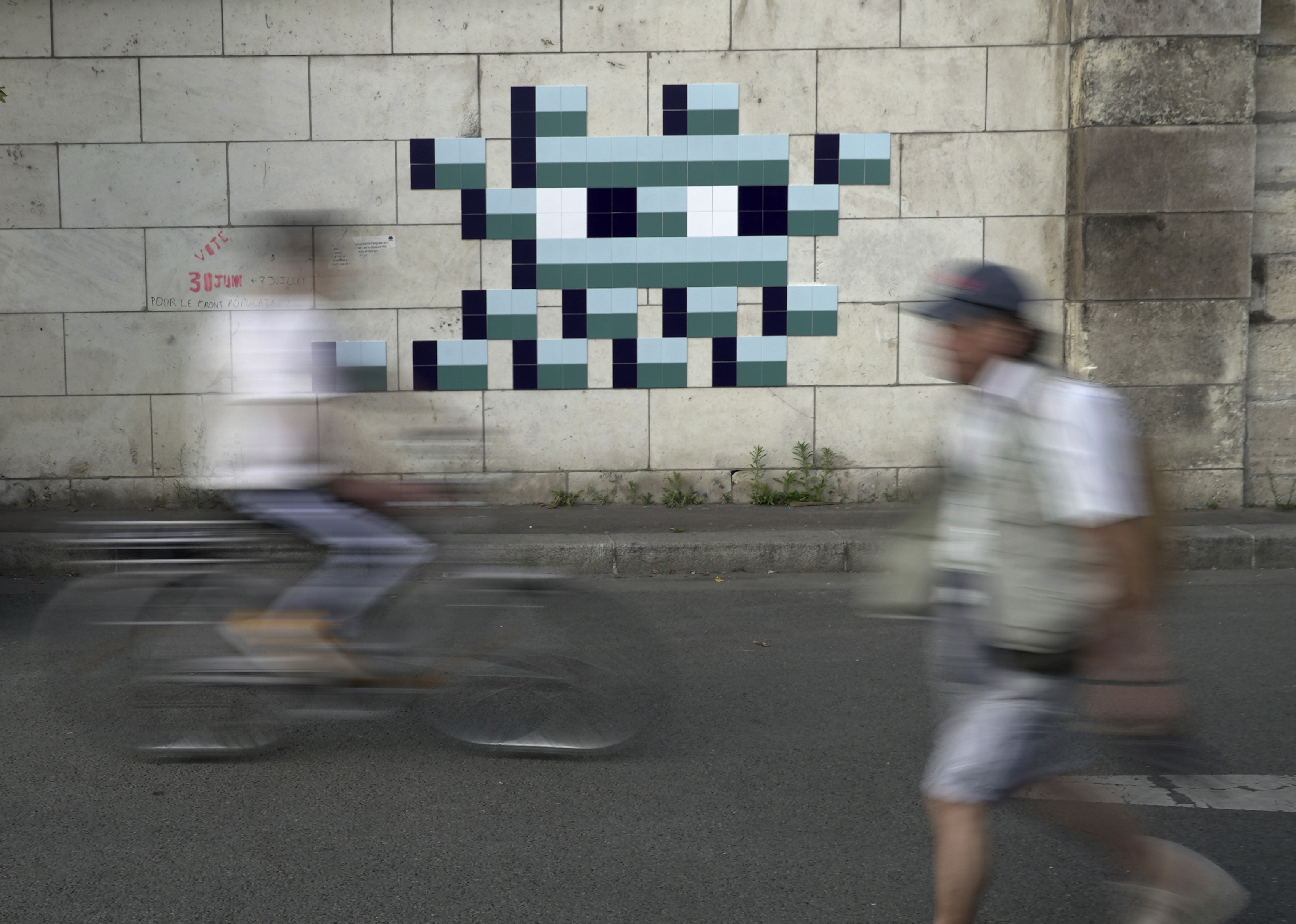 A cyclist rides in front of an Olympic-themed new mosaic by the mysterious French street artist known only by the name Invader, Wednesday Aug. 7, 2024, on the banks of the Seine River, during the 2004 Summer Olympics, in Paris, France. 