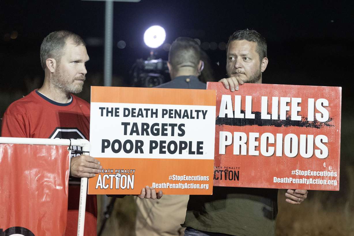 Tom Leon, right, from Draper and Jacob Blackwell, left, from Salt Lake City, protest with Death Penalty Action during a gathering held in a Free Speech Zone established by the Utah Department of Corrections near the Utah State Correctional Facility in Salt Lake City before the execution of Taberon Honie on Wednesday.
