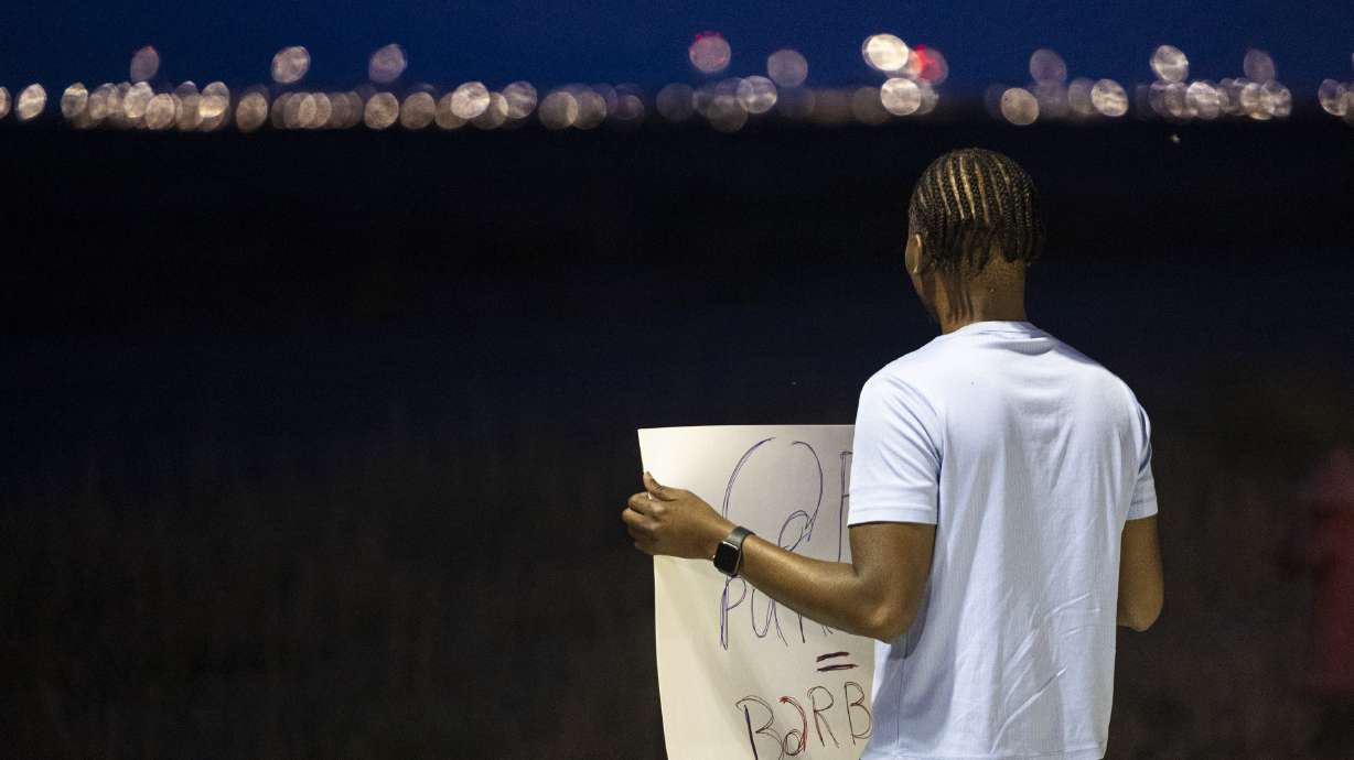 Rony Charles, of Salt Lake City, holds a sign as he looks in the direction of the Utah State Correctional Facility during a gathering held in a free speech zone near the facility in Salt Lake City before the execution of Taberon Honie on Wednesday.