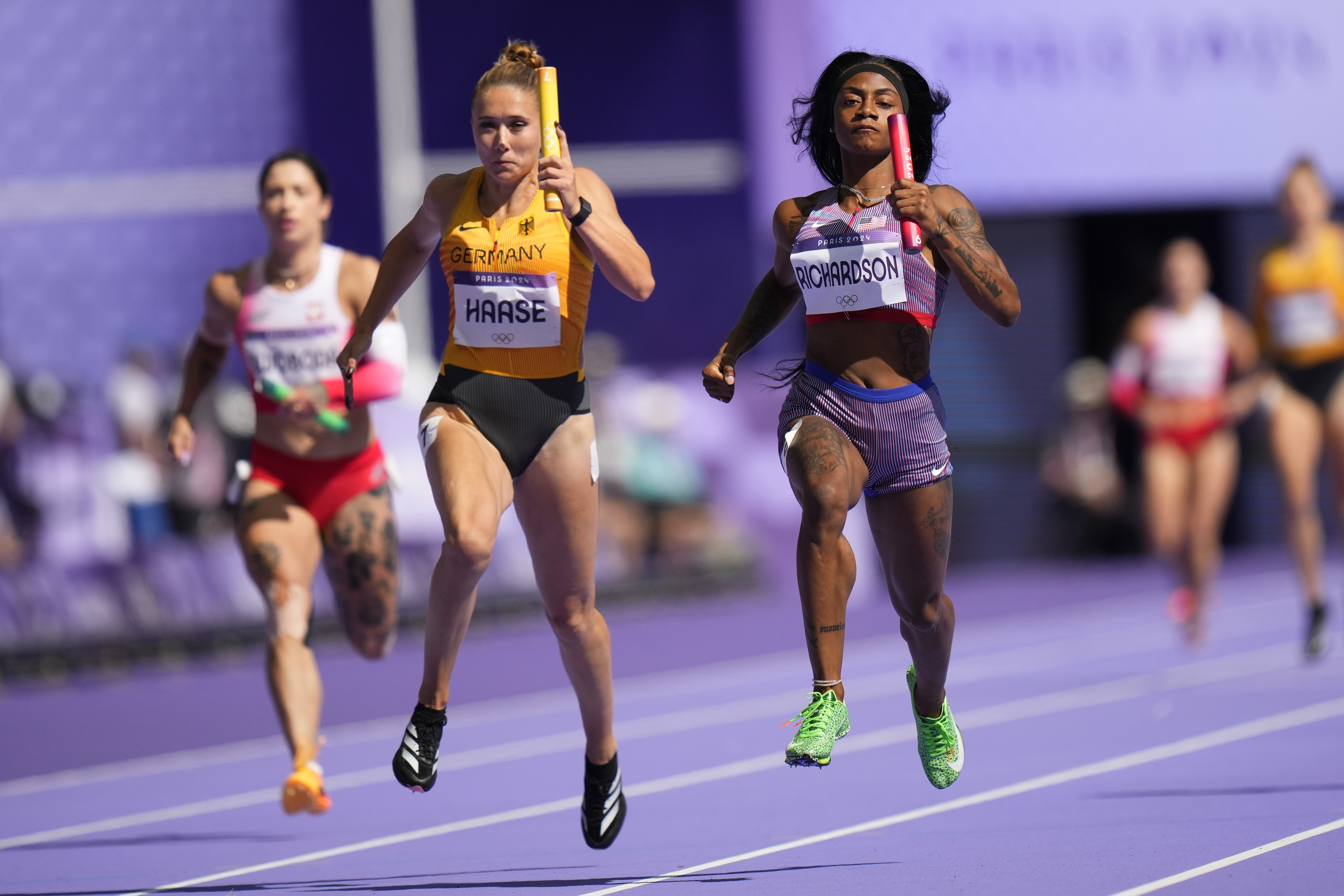 Sha'carri Richardson, right, of the United States, and Rebekka Haase, of Germany, in the women's 4x100-meter relay heat at the 2024 Summer Olympics, Thursday, Aug. 8, 2024, in Saint-Denis, France. 
