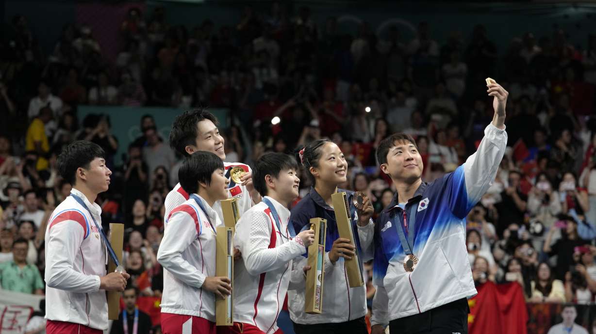FILE - South Korea's Lim Jonghoon, right, takes a selfie with North Korea's Ri Jong Sik, left, and Kim Kum, second left, China's Wang Chuqin, background, and Sun Yingsha, center, and his teammate Shin Yubin, right, and Lim Jonghoon during the medal ceremony at the 2024 Summer Olympics, July 30, 2024, in Paris, France.
