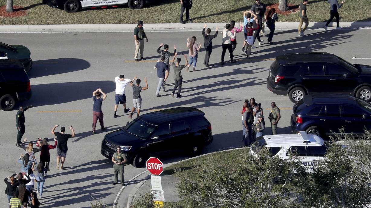Students evacuate Marjory Stoneman Douglas High School in Parkland, Fla., after a shooter opened fire on the campus on Feb. 14, 2018. Families of three students murdered in the shooting have reached multimillion-dollar settlements in a lawsuit against the shooter.