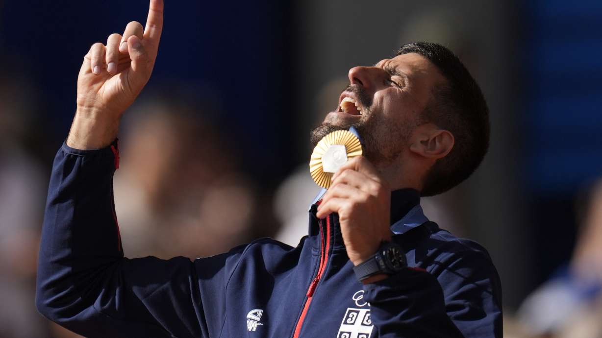 Serbia's Novak Djokovic shows his gold medal after defeating Spain's Carlos Alcaraz in the men's singles tennis final at the Roland Garros stadium during the 2024 Summer Olympics, Sunday, Aug. 4, 2024, in Paris, France. Djokovic has won his first Olympic gold medal by beating Alcaraz 7-6 (3), 7-6 (2) in the 2024 Games men's tennis singles final.