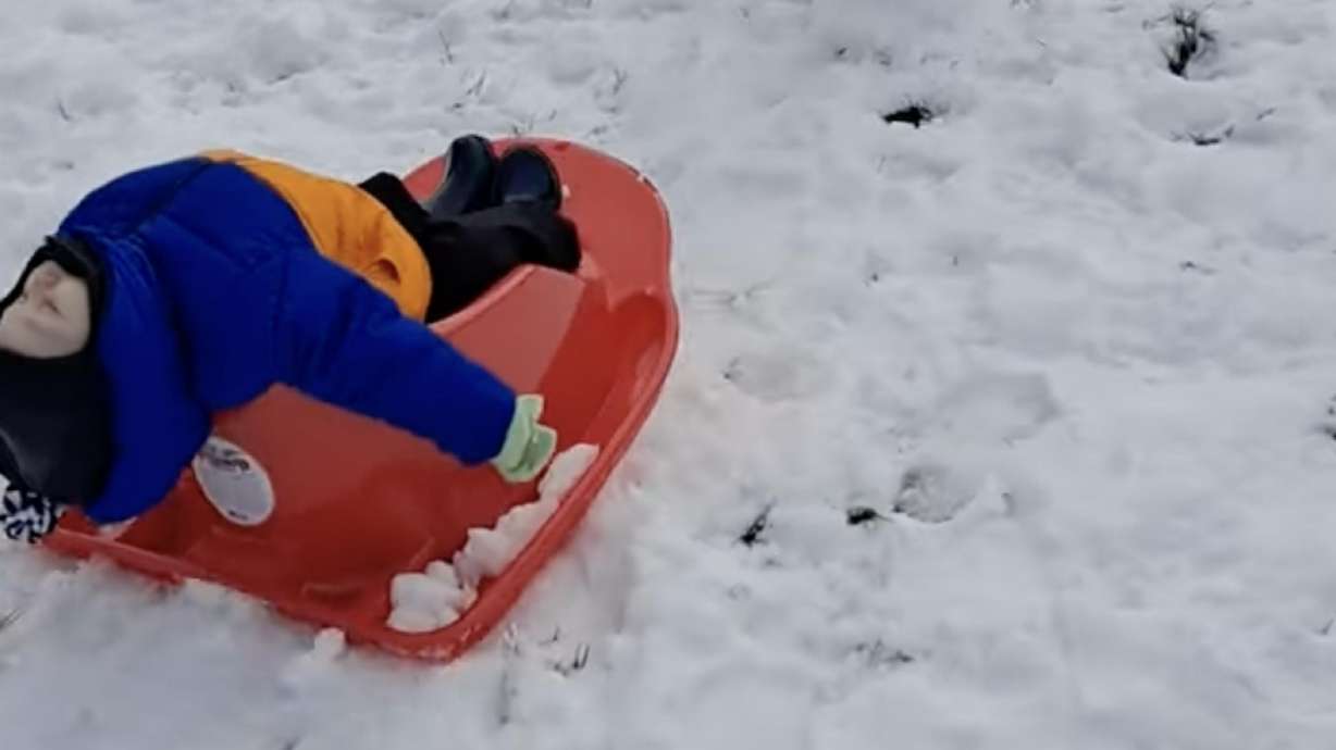 A baby is pulled in a sled while fast asleep.