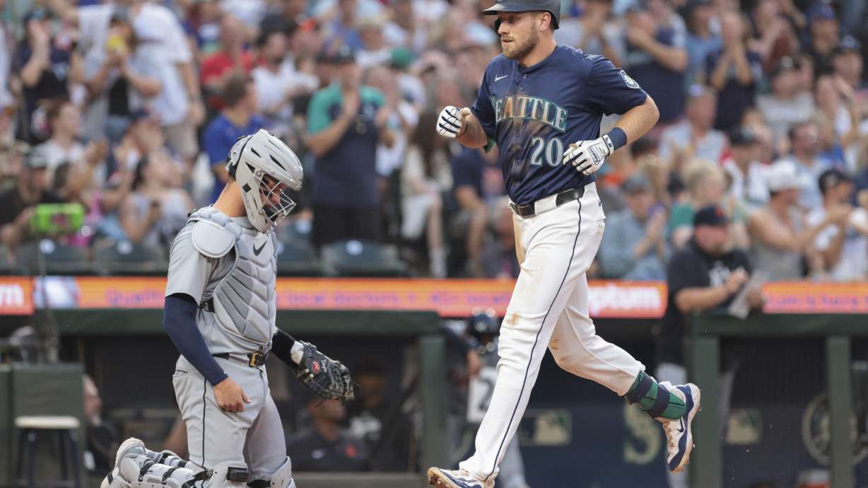 Seattle Mariners' Luke Raley (20) crosses home after hitting a home run as Detroit Tigers catcher Dillon Dingler, left, looks on during the sixth inning of a baseball game, Thursday, Aug. 8, 2024, in Seattle.