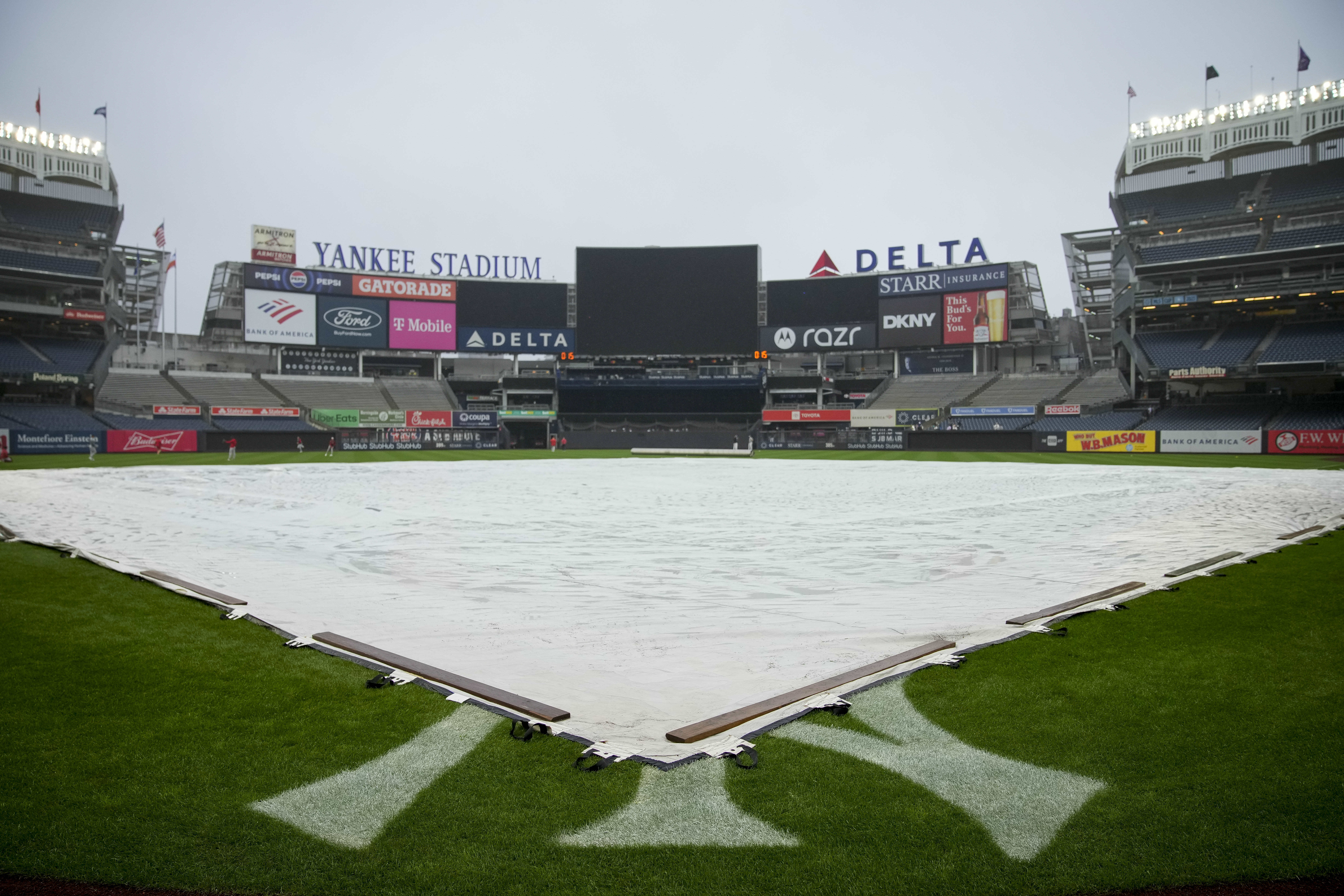 A tarp covers the field at Yankee Stadium before a baseball game between the New York Yankees and the Los Angeles Angels, Thursday, Aug. 8, 2024, in New York.