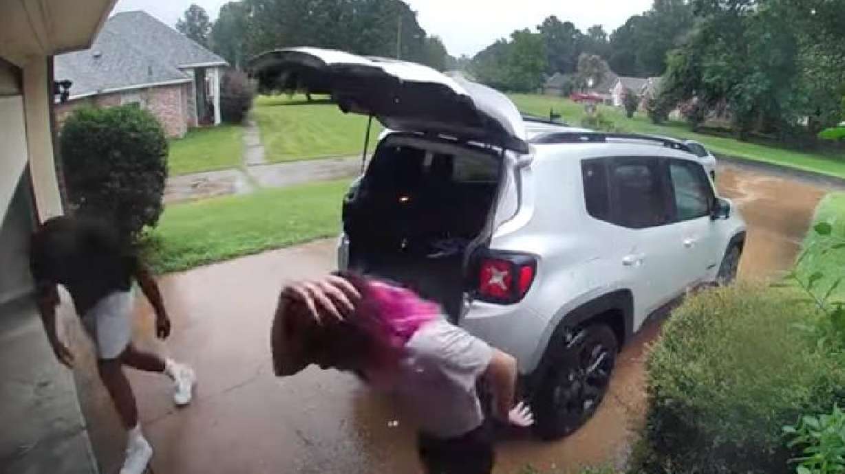 Man and woman duck under a garage door to get out of the rain, July 27, in Shreveport, Louisiana. There are worse things than a little rain.