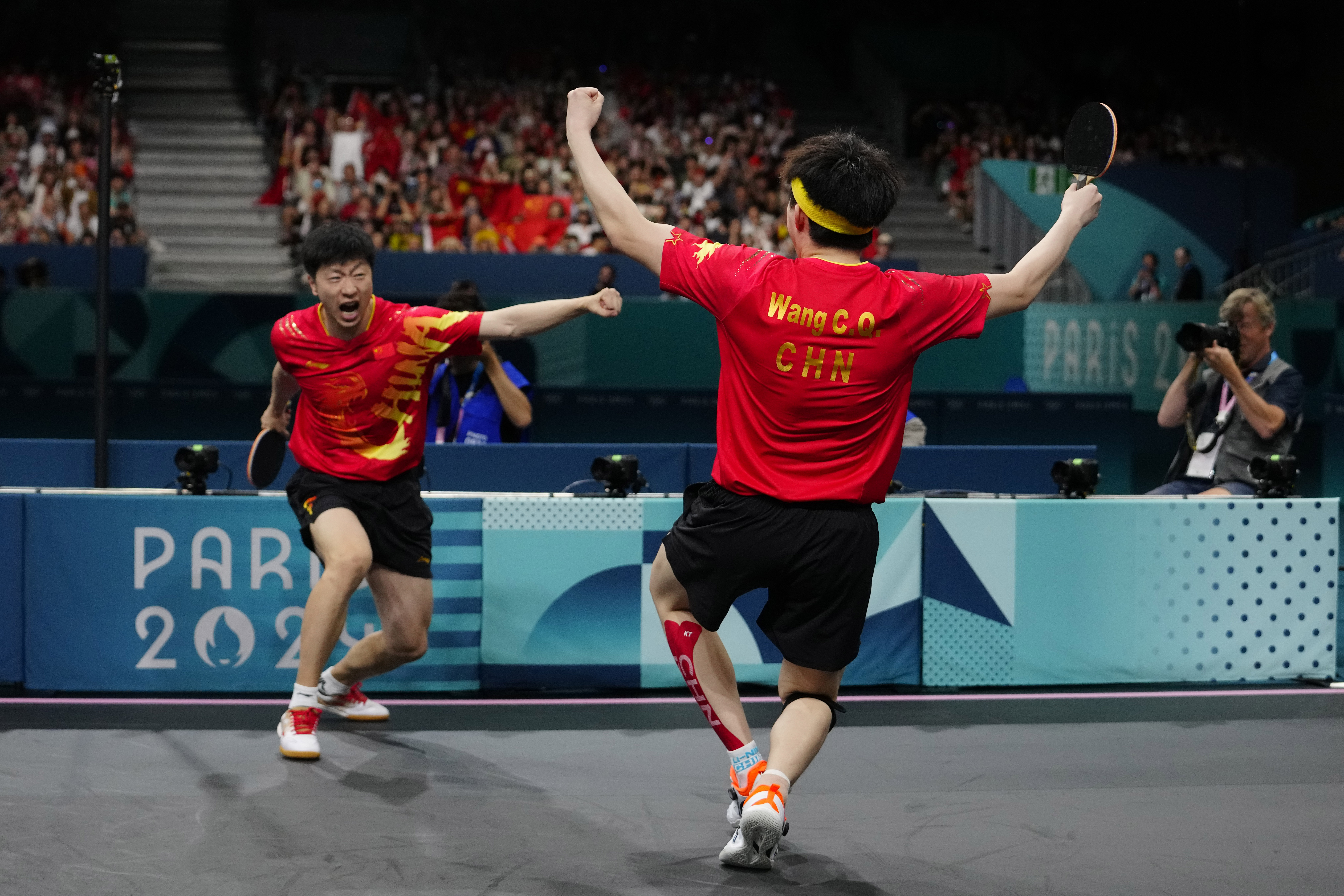 China's Ma Long, background, and Wang Chuqin celebrate after defeating Sweden's Anton Kallberg and Kristian Karlsson during the men's gold medal team table tennis match at the 2024 Summer Olympics, Friday, Aug. 9, 2024, in Paris, France. 