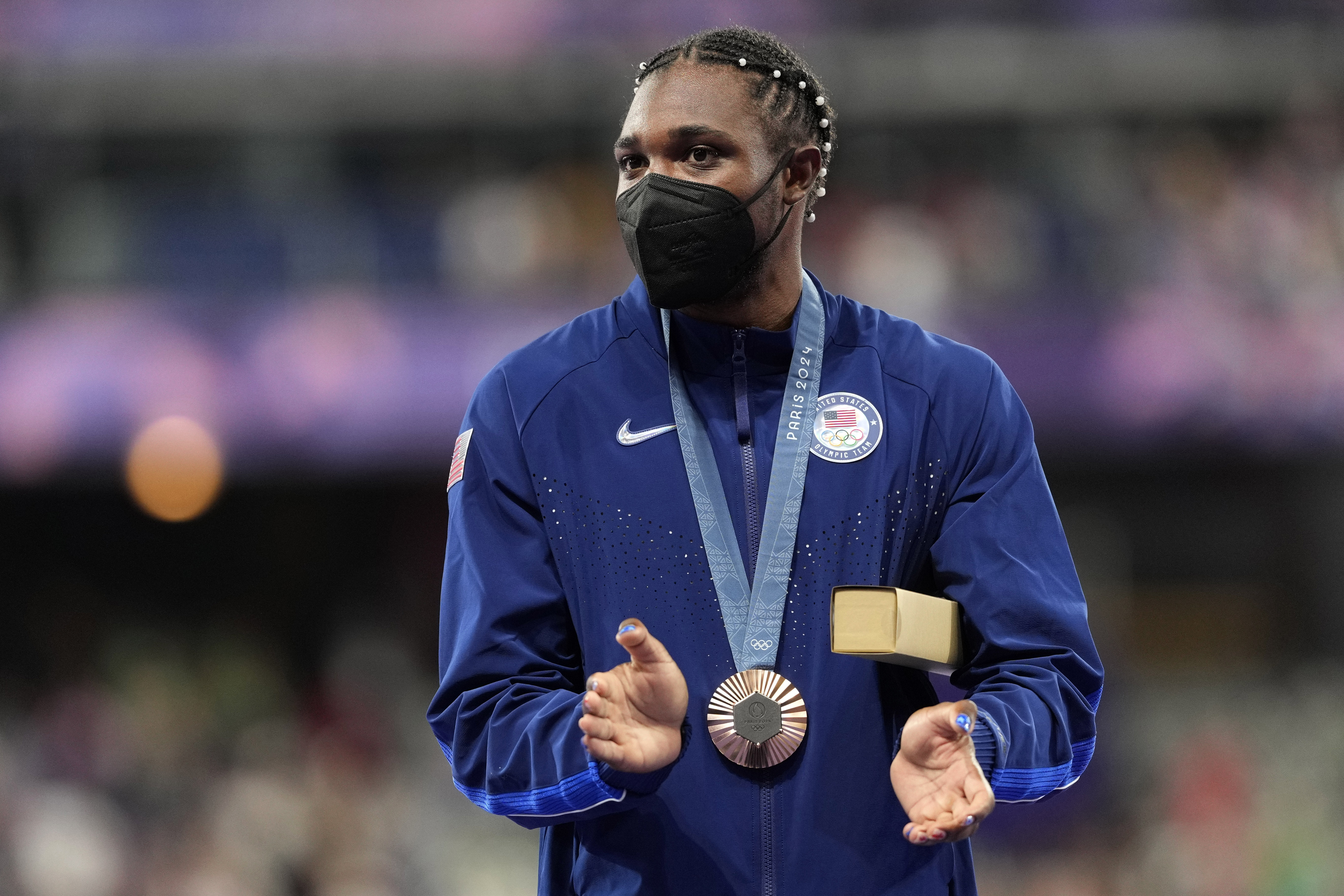Men's 200-meter bronze medalist, Noah Lyles, of the United States, applauds while standing on the podium at the 2024 Summer Olympics, Friday, Aug. 9, 2024, in Saint-Denis, France. 