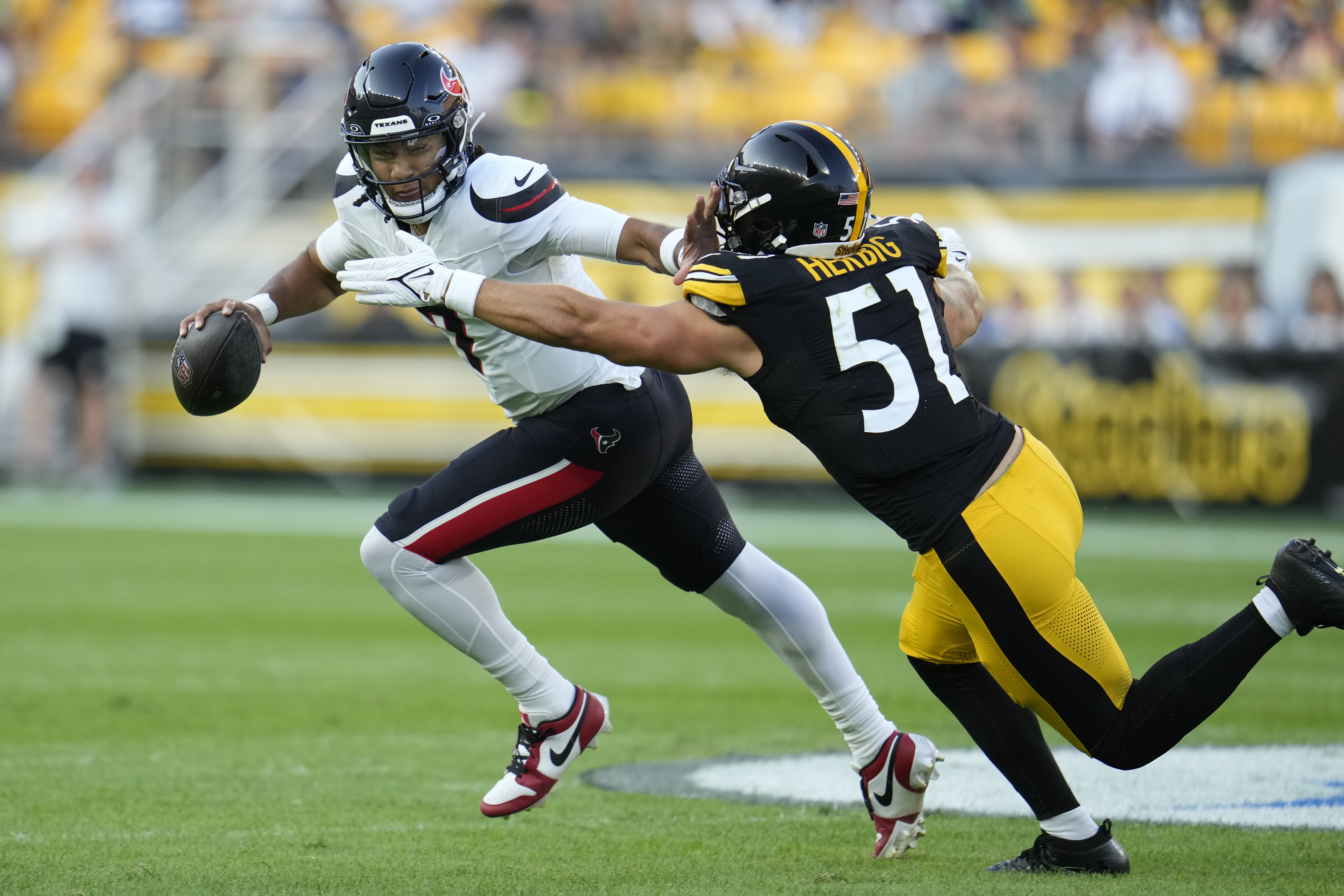 Houston Texans quarterback C.J. Stroud, left, attempts to avoid Pittsburgh Steelers linebacker Nick Herbig, right, in the first half of a preseason NFL football game, Friday, Aug. 9, 2024, in Pittsburgh. 