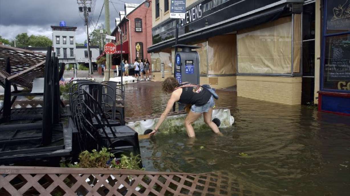 Kari Lynch pick up trash from flood waters near the City Dock in Annapolis, Md., on Friday. First responders launched high-water and helicopter rescues of people trapped in cars and homes along the East coast.