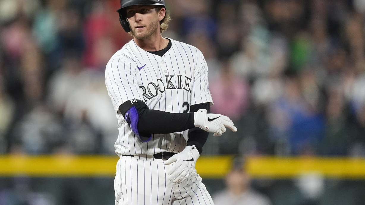 Colorado Rockies' Ryan McMahon gestures to the dugout after hitting an RBI double off Atlanta Braves relief pitcher A.J. Minter in the seventh inning of a baseball game Friday, Aug. 9, 2024, in Denver.