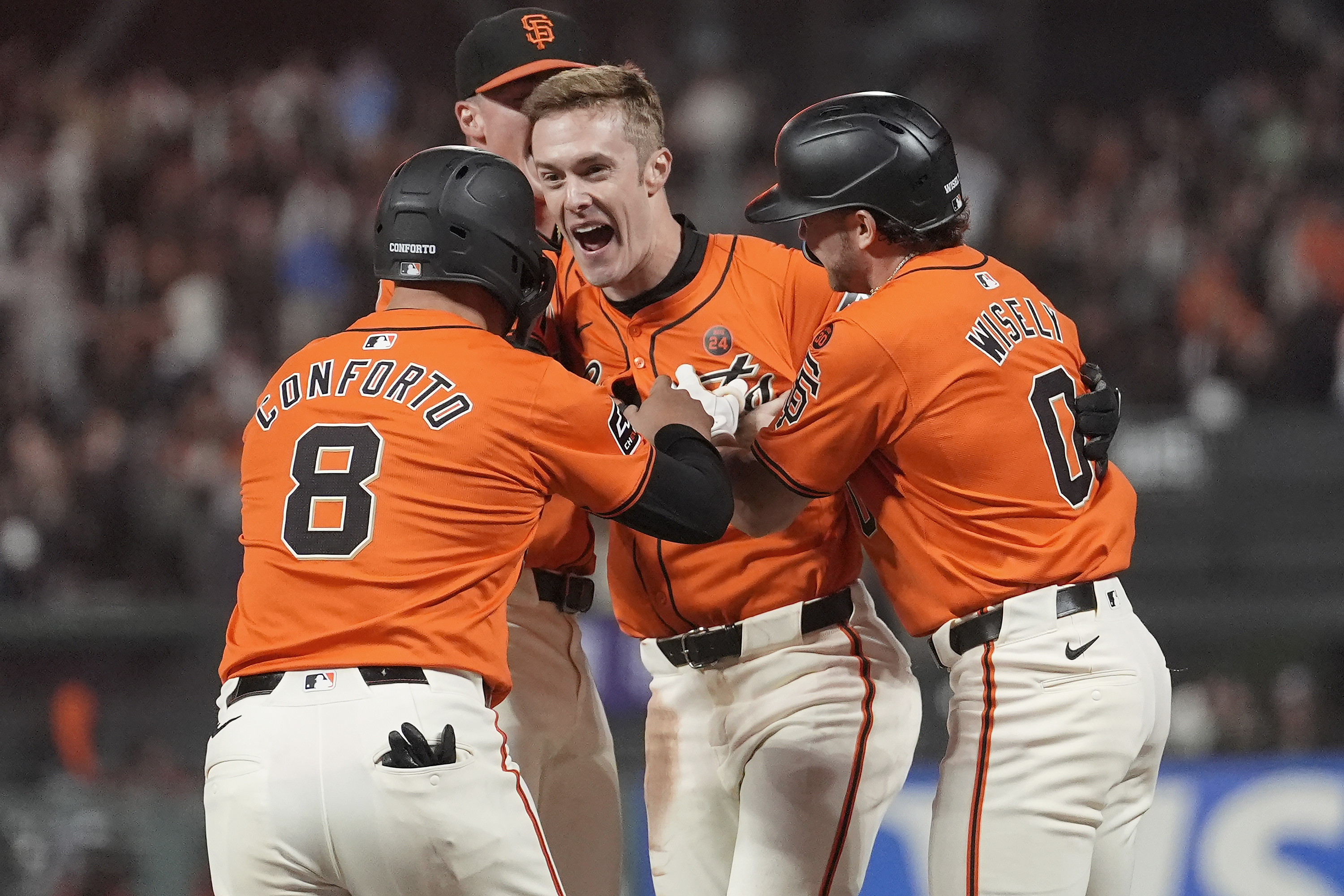 San Francisco Giants' Mark Canha, middle, is congratulated by teammates after hitting a sacrifice fly that scored Michael Conforto (8) for the winning run during the ninth inning of a baseball game against the Detroit Tigers in San Francisco, Friday, Aug. 9, 2024.