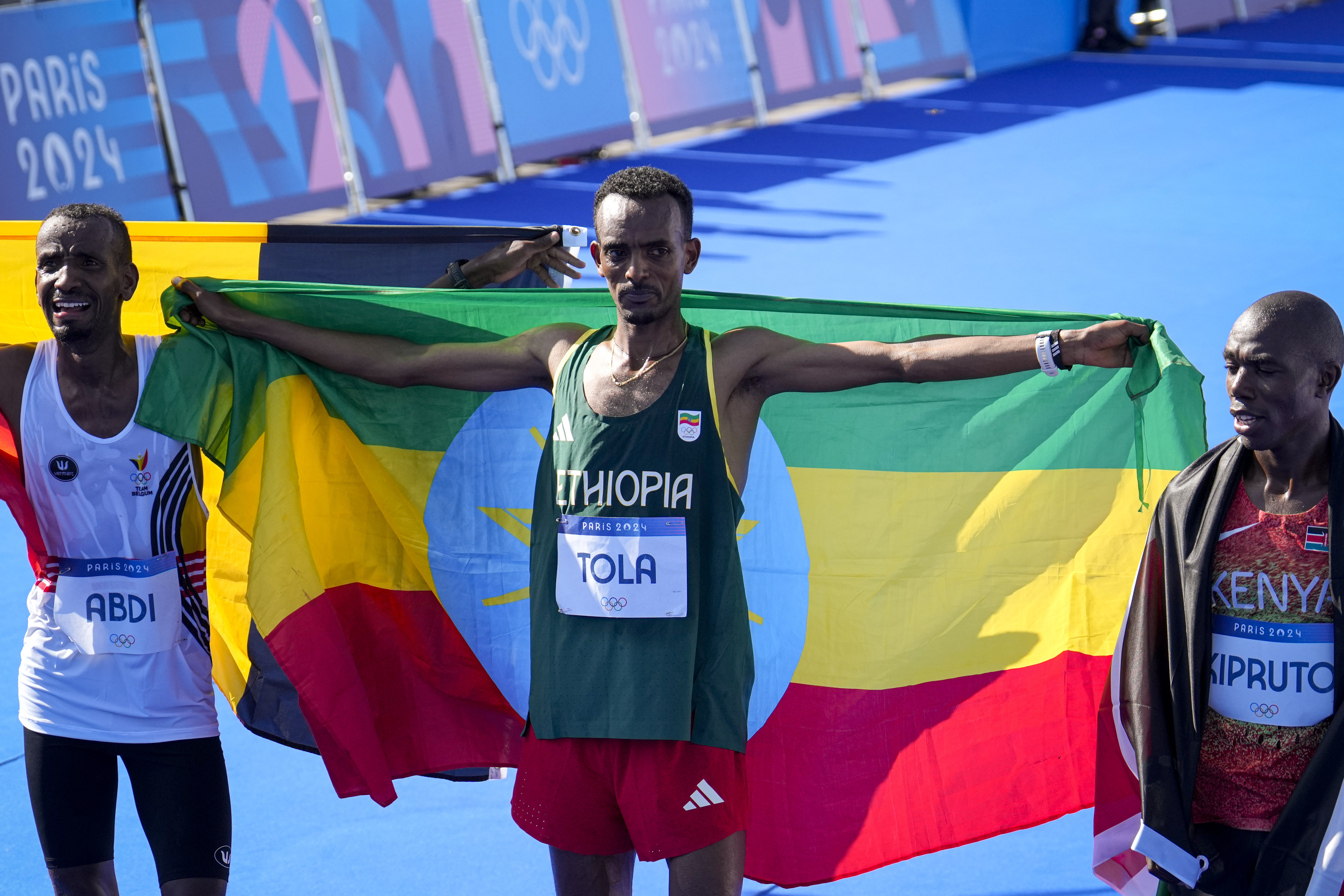 Belgium's Bashir Abdi, left, Ethiopia's Tamirat Tola, center, and Kenya's Benson Kipruto, right, celebrate after crossing the finish line at the end of the men's marathon competition at the 2024 Summer Olympics, Saturday, Aug. 10, 2024, in Paris, France. 