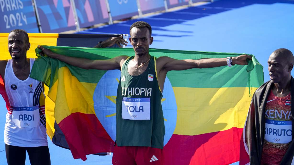 Belgium's Bashir Abdi, left, Ethiopia's Tamirat Tola, center, and Kenya's Benson Kipruto, right, celebrate after crossing the finish line at the end of the men's marathon competition at the 2024 Summer Olympics, Saturday, Aug. 10, 2024, in Paris, France.