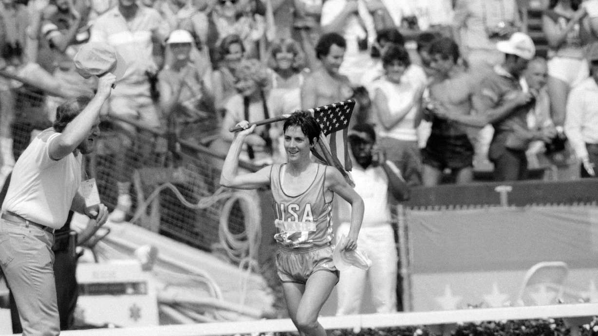 FILE - Twenty-seven-year-old Joan Benoit of Freeport, Maine, waves the American flag enthusiastically on Aug. 5, 1984, in Los Angeles after finishing the first-ever Olympic women's marathon in the fastest-ever time for that distance. 2.24:52 for the 26-mile, 385-yard course.