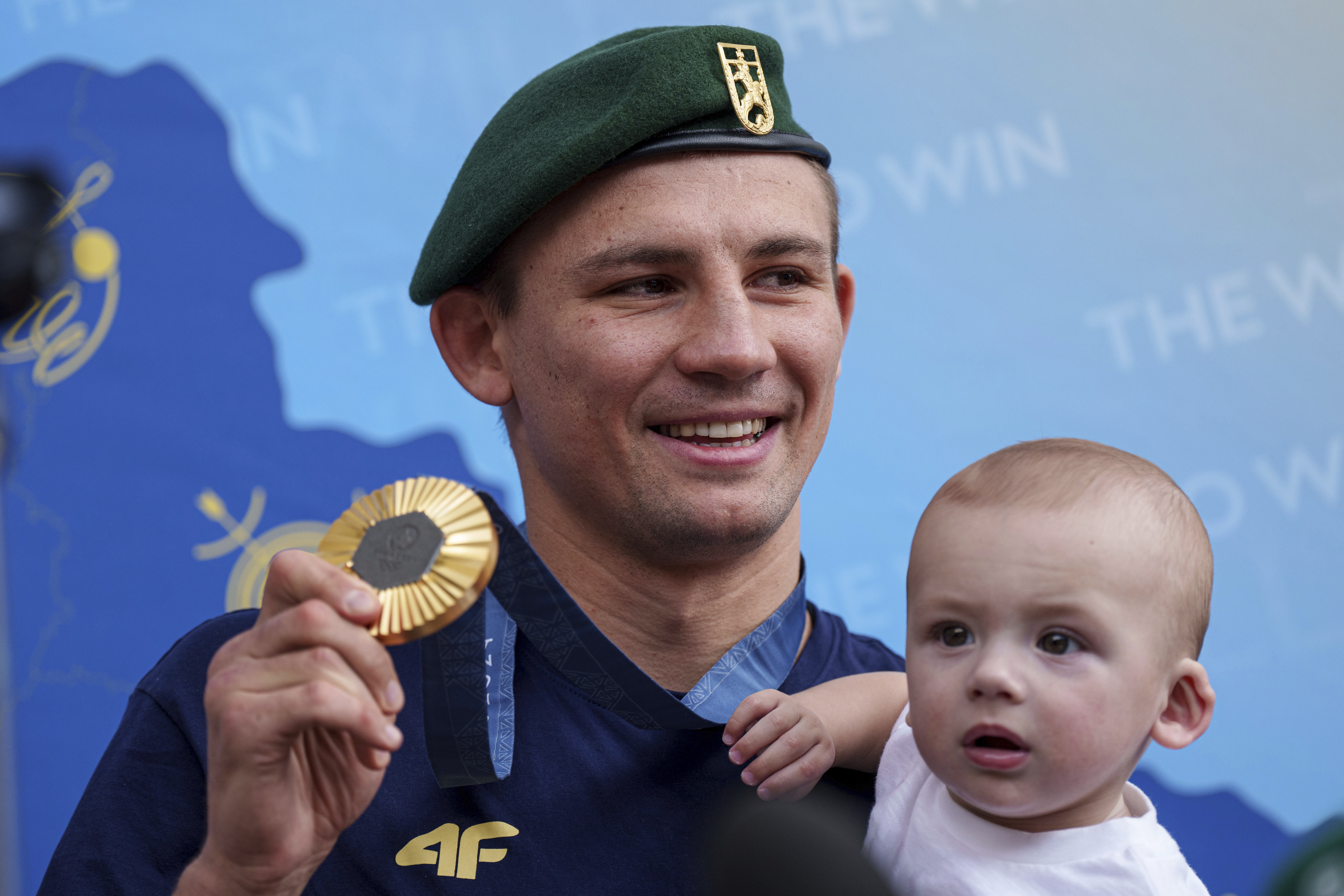 Oleksandr Khyzhniak, Ukraine's Gold medalist of the 2024 Summer Olympics for the men's 80 kg boxing, shows his medal while holding his son Oleksandr after arriving at the train station in Kyiv, Ukraine, Saturday, Aug. 10, 2024. 