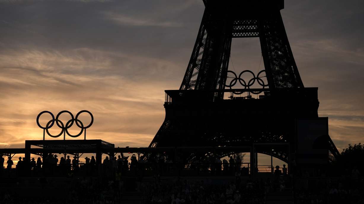 Spectators watch a quarterfinal beach volleyball match between Australia and Switzerland at sunset at Eiffel Tower Stadium at the 2024 Summer Olympics, Tuesday, Aug. 6, 2024, in Paris, France.