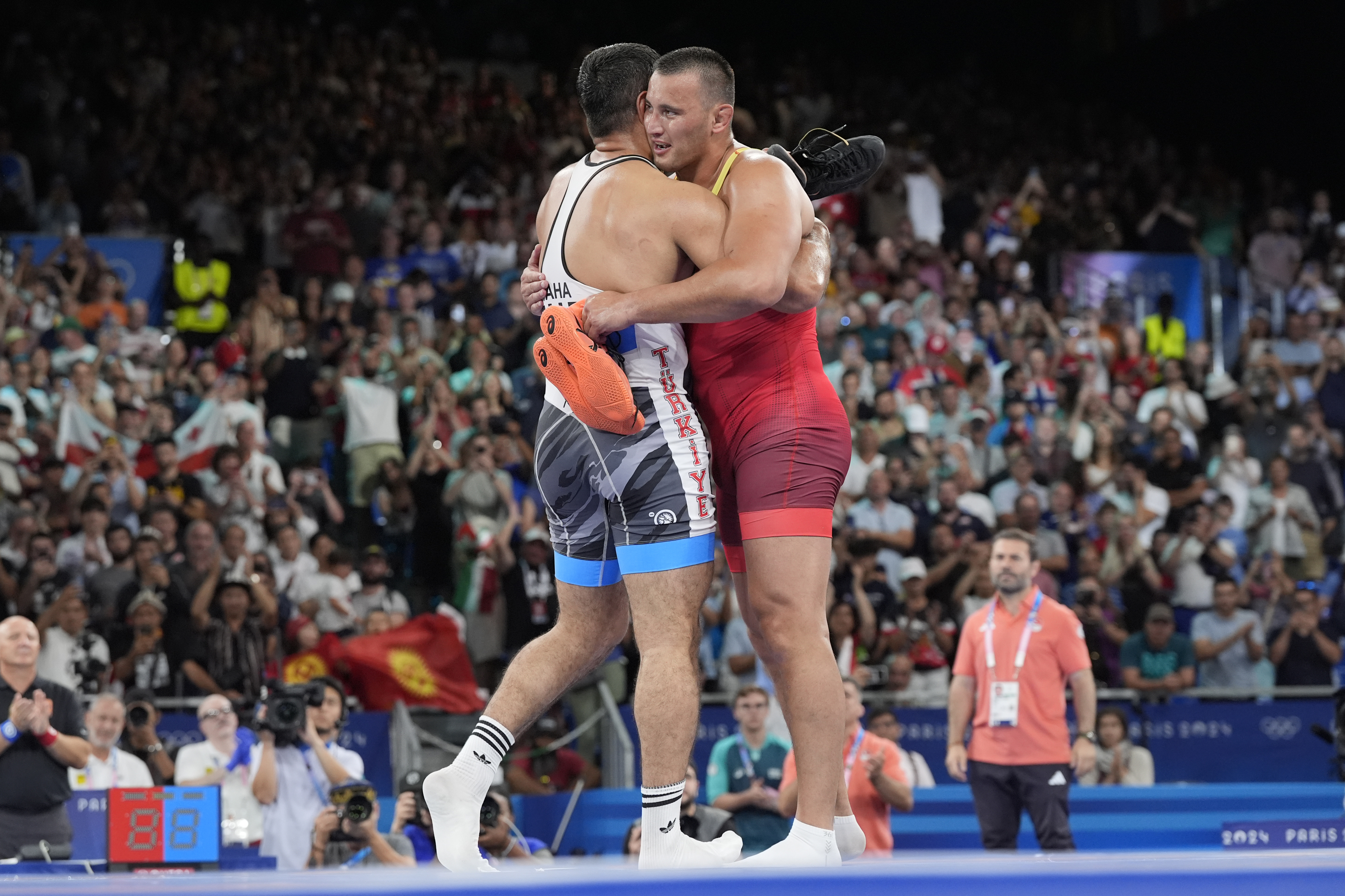 Kyrgyzstan's Aiaal Lazarev and Turkey's Taha Akgul embrace as they take off their shoes, retiring after their men's freestyle 125kg bronze medal wrestling match, at Champ-de-Mars Arena, during the 2024 Summer Olympics, Saturday, Aug. 10, 2024, in Paris, France.