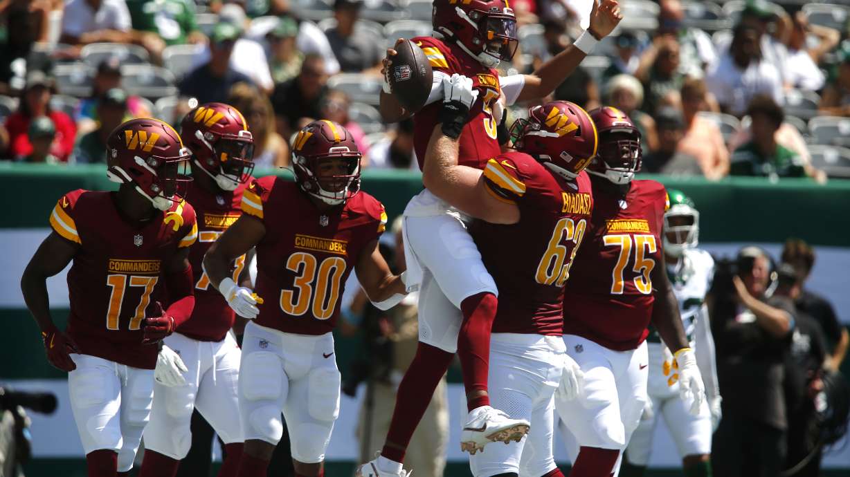 Washington Commanders quarterback Jayden Daniels (5) is congratulated by teammate Tyler Biadasz (63) after scoring during the first half of an NFL preseason football game against the New York Jets Saturday, Aug. 10, 2024, in East Rutherford. N.J.