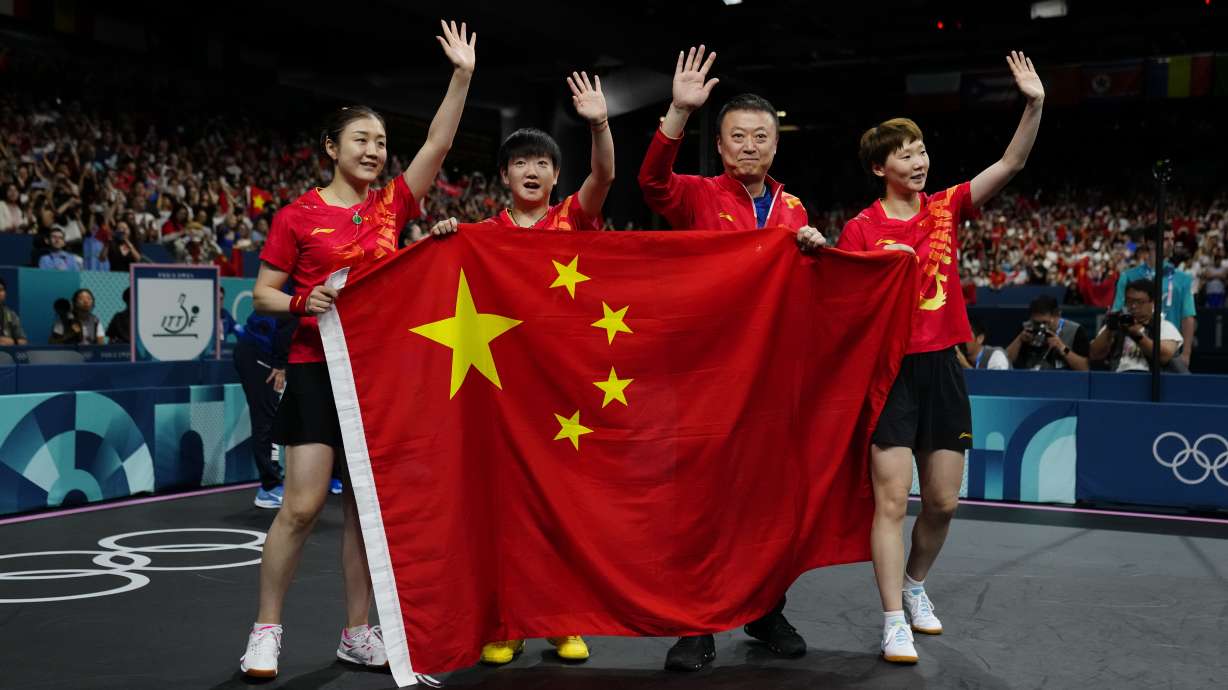 China team hold the flag of their country after defeating Japan in the women's gold medal team table tennis match at the 2024 Summer Olympics, Saturday, Aug. 10, 2024, in Paris, France.
