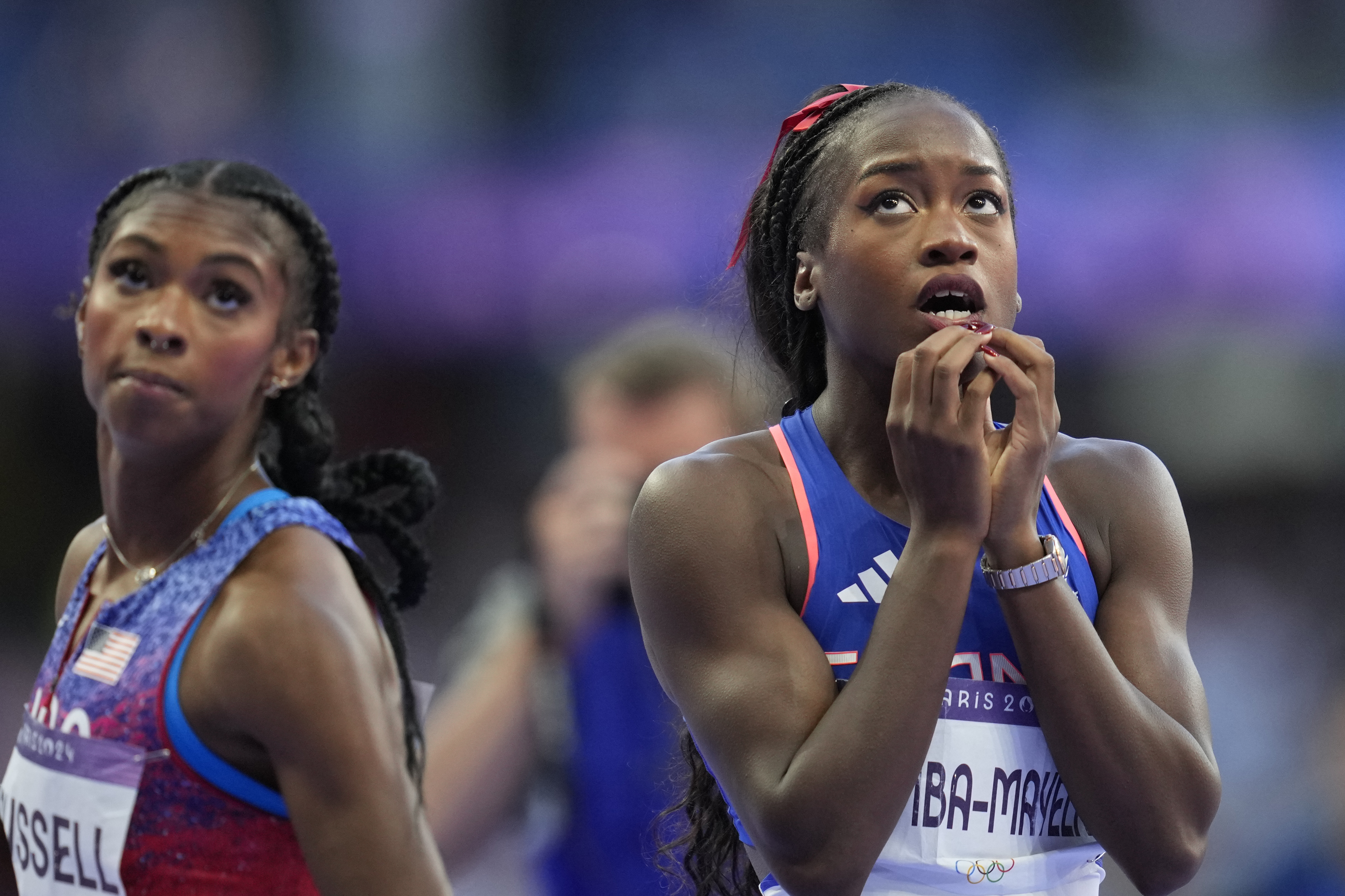 Gold medalist Masai Russell, of the United States, left, and silver medalist Cyréna Samba-Mayela, of France, wait for the official results after finishing in the women's 100 meters hurdles final at the 2024 Summer Olympics, Saturday, Aug. 10, 2024, in Saint-Denis, France.