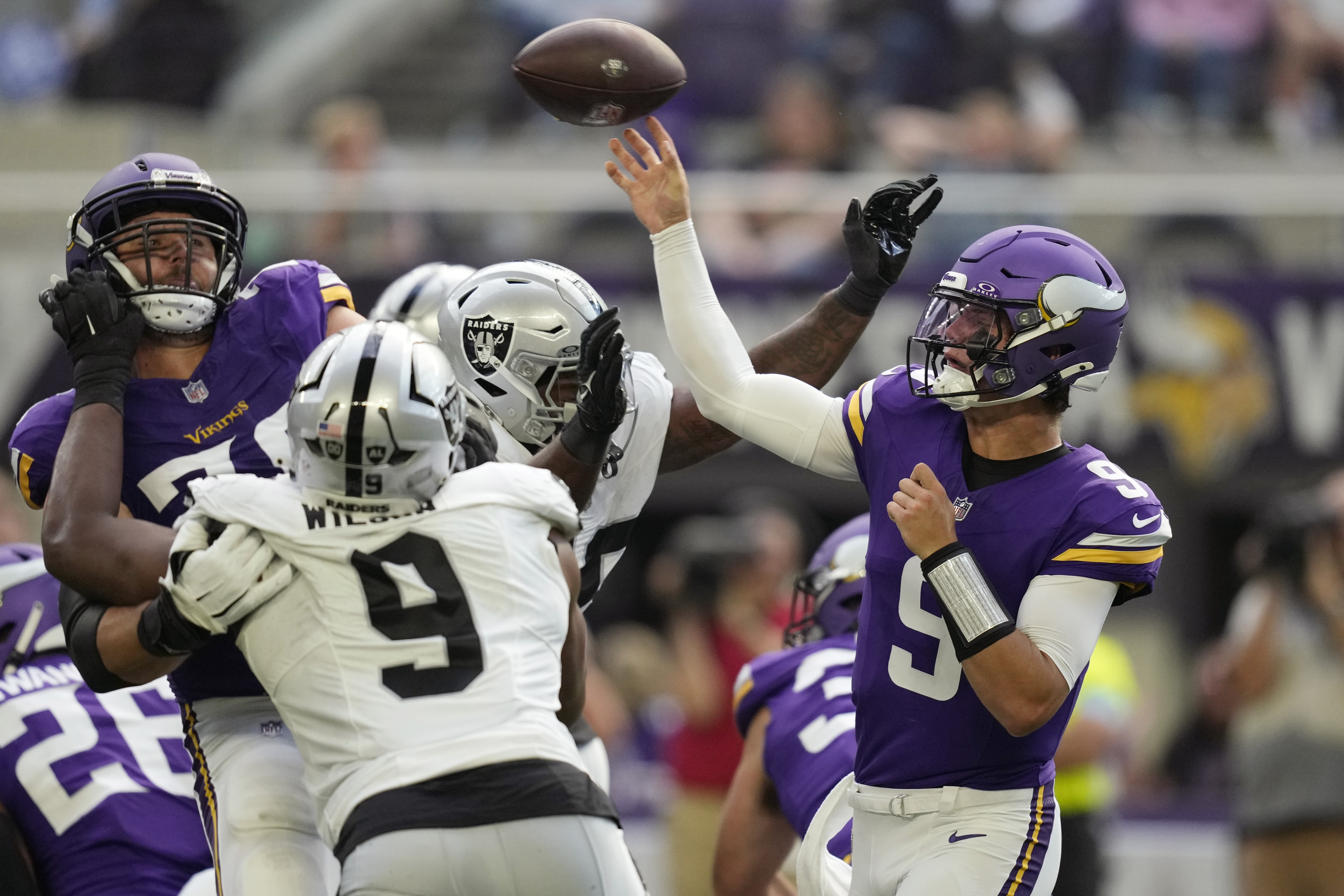 Minnesota Vikings quarterback J.J. McCarthy (9) throws against the Las Vegas Raiders under pressure during the first half of an NFL football game Saturday, Aug. 10, 2024, in Minneapolis. 