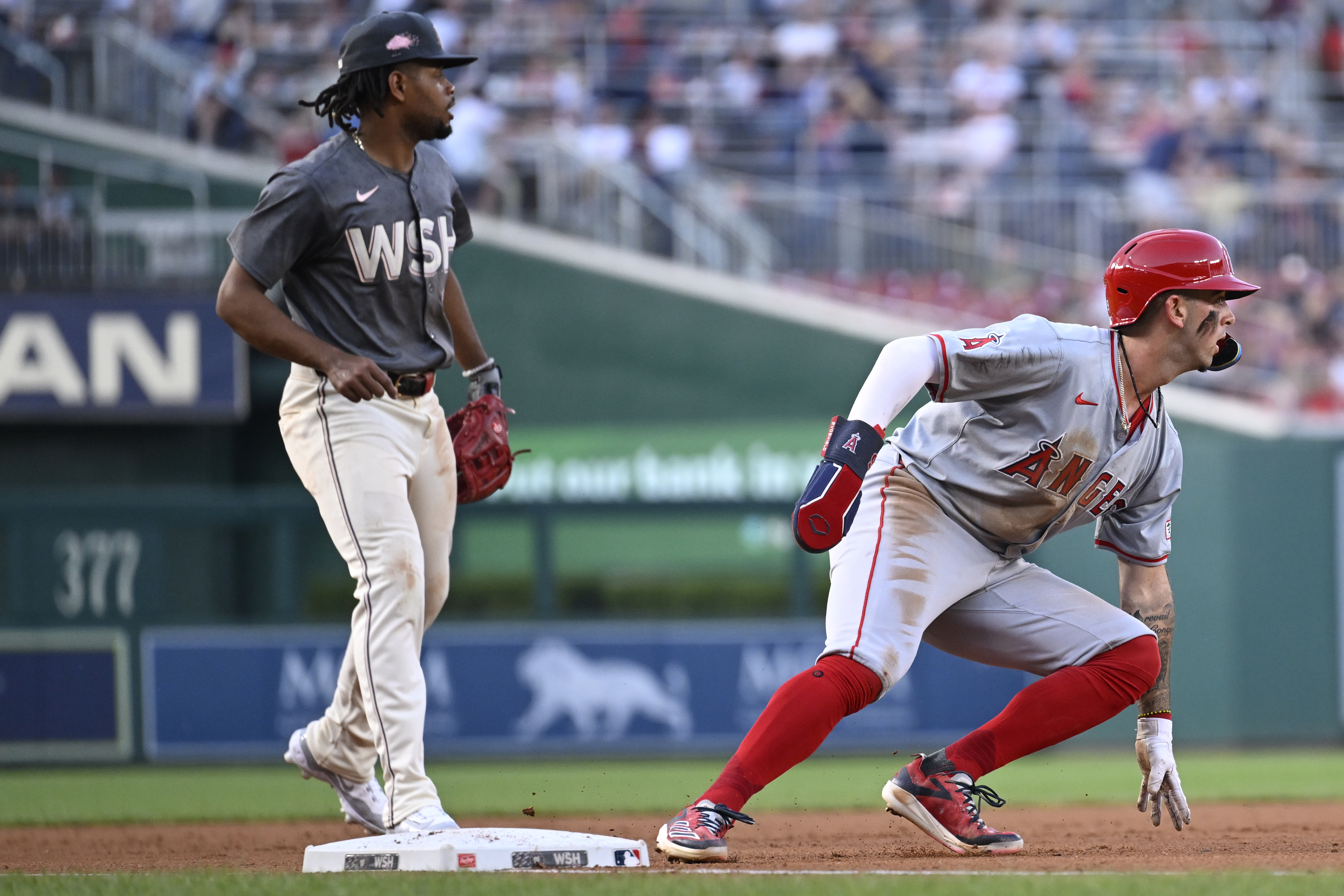 Washington Nationals third baseman Jose Tena, left, watches as Los Angeles Angels' Zach Neto turns back to second base when a fly ball by Angels' Kevin Pillar was caught, resulting in a double play, to end the third inning of a baseball game, Saturday, Aug. 10, 2024, in Washington. 