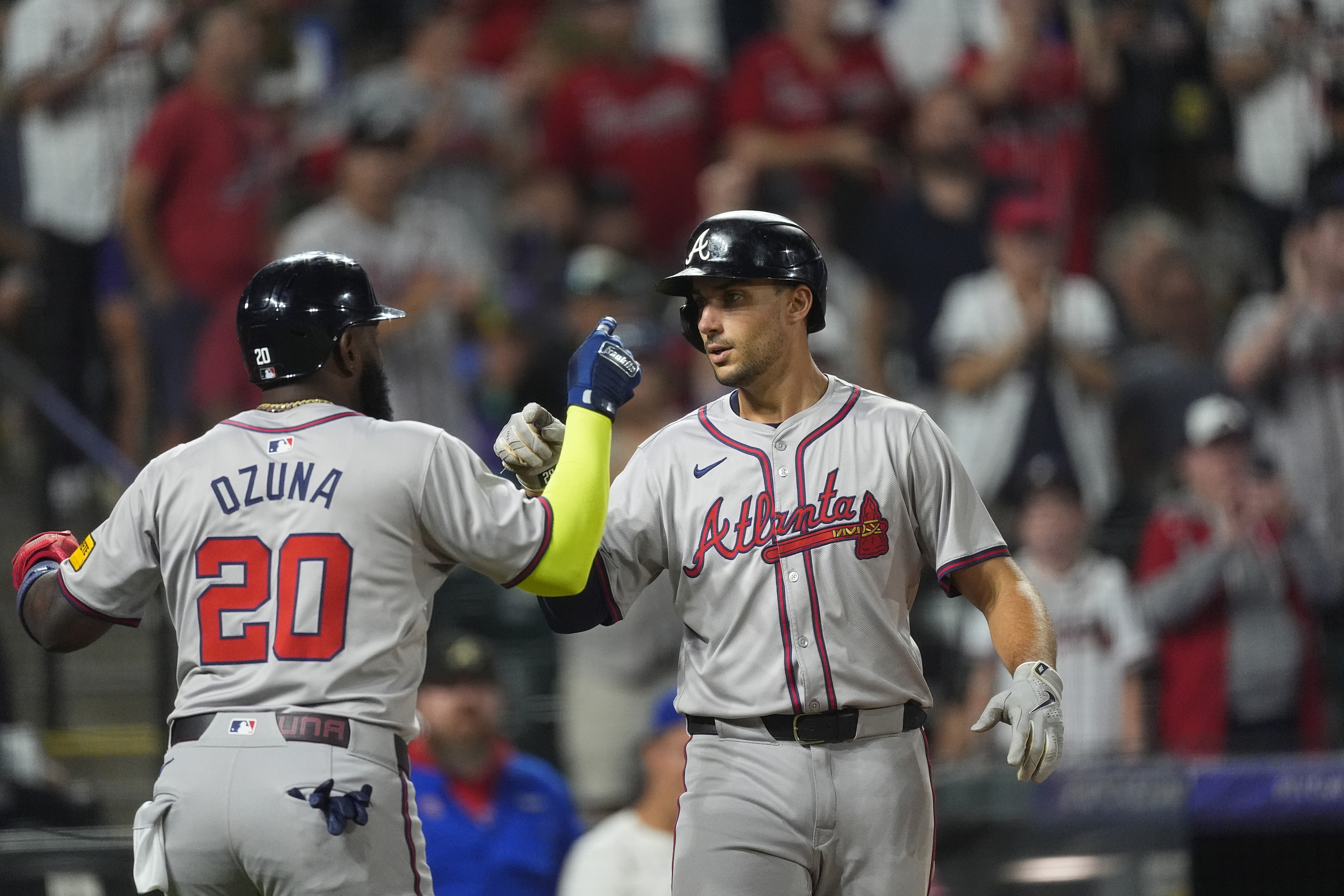 Atlanta Braves' Marcell Ozuna, left, congratulates Matt Olson, right, who crosses home plate after hitting a two-run home run off Colorado Rockies relief pitcher Angel Chivilli in the seventh inning of a baseball game Saturday, Aug. 10, 2024, in Denver. 