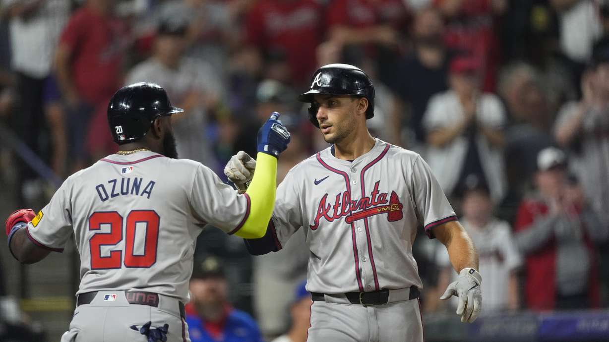 Atlanta Braves' Marcell Ozuna, left, congratulates Matt Olson, right, who crosses home plate after hitting a two-run home run off Colorado Rockies relief pitcher Angel Chivilli in the seventh inning of a baseball game Saturday, Aug. 10, 2024, in Denver.