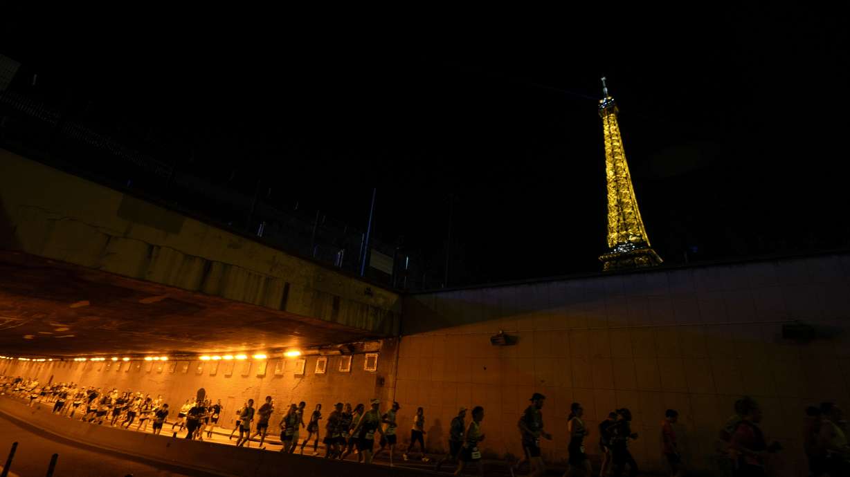 Runners run through an underpass near the Eiffel Tower as they participate in the marathon Pour Tous, at the 2024 Summer Olympics, Saturday, Aug. 10, 2024, in Paris, France.