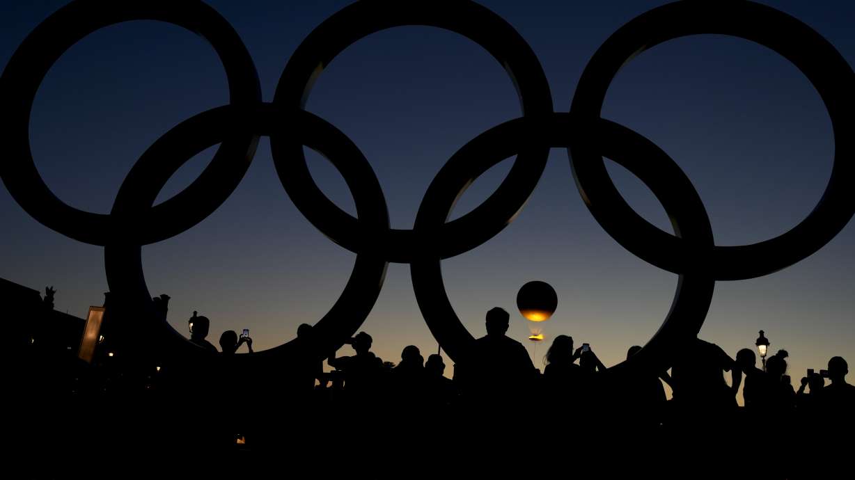 People watch the cauldron rise at sunset by the Olympic rings during the 2024 Summer Olympics, Monday, Aug. 5, 2024, in Paris, France.