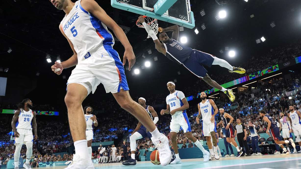 United States' LeBron James, right dunks as France's Nicolas Batum walks away during a men's gold medal basketball game at Bercy Arena at the 2024 Summer Olympics, Saturday, Aug. 10, 2024, in Paris, France.