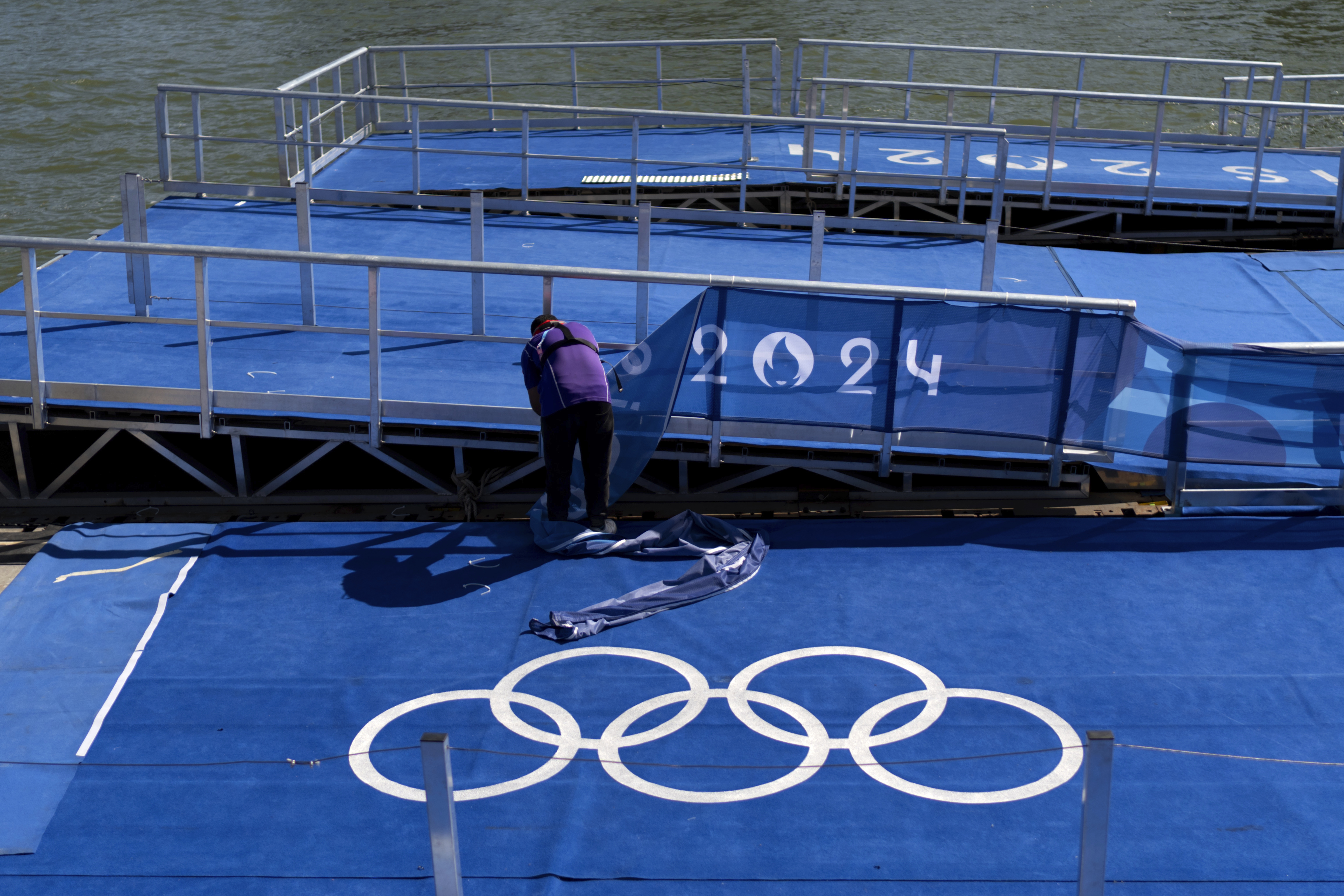 A worker takes down Olympic signage from the pontoon used for swim events along the Seine River ahead of tomorrow's closing ceremony at the 2024 Summer Olympics, Saturday, Aug. 10, 2024, in Paris, France. 