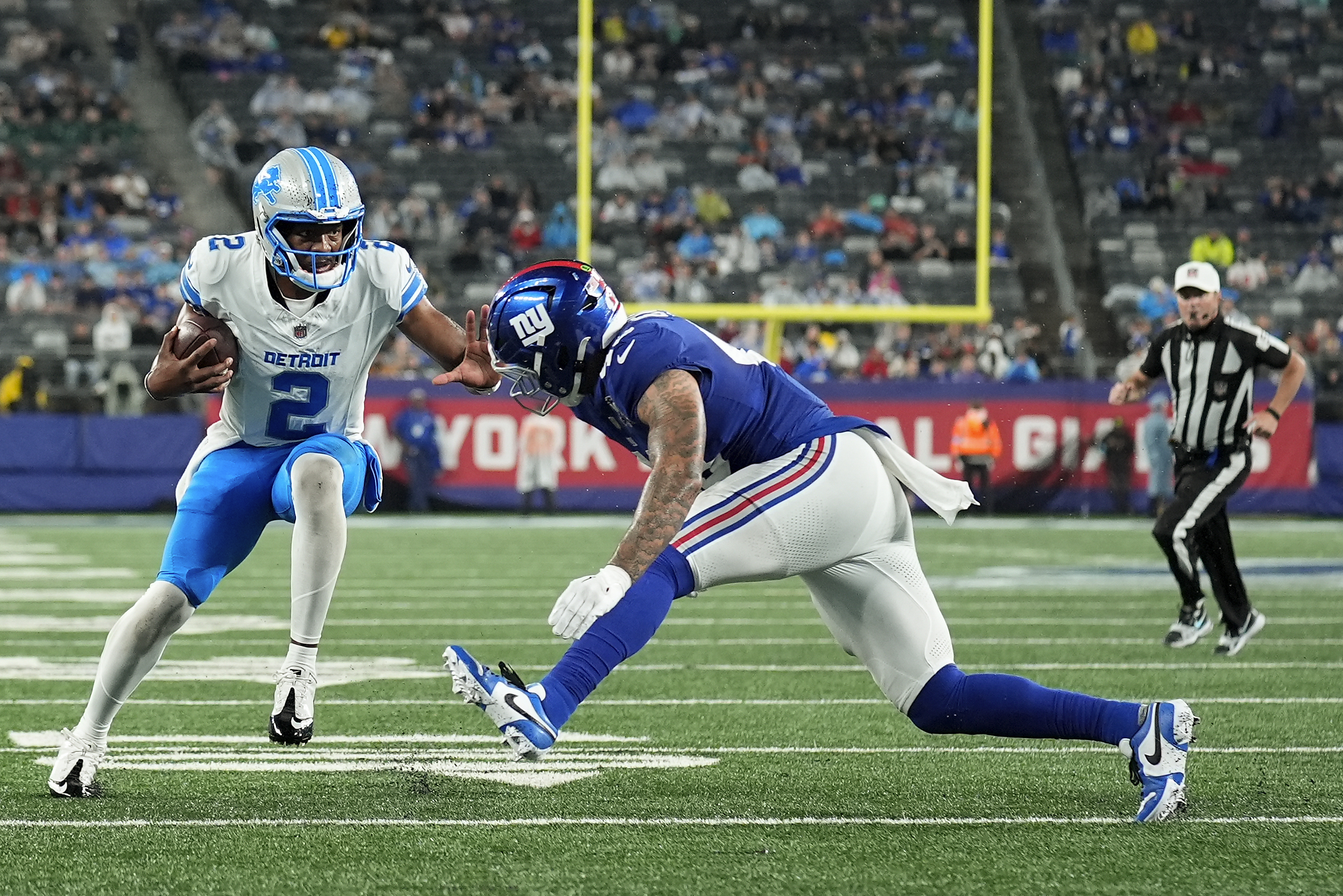 Detroit Lions quarterback Hendon Hooker (2) carries the ball against New York Giants linebacker Darrian Beavers (43) during the third quarter of an NFL football game, Thursday, Aug. 8, 2024, in East Rutherford, N.J. 