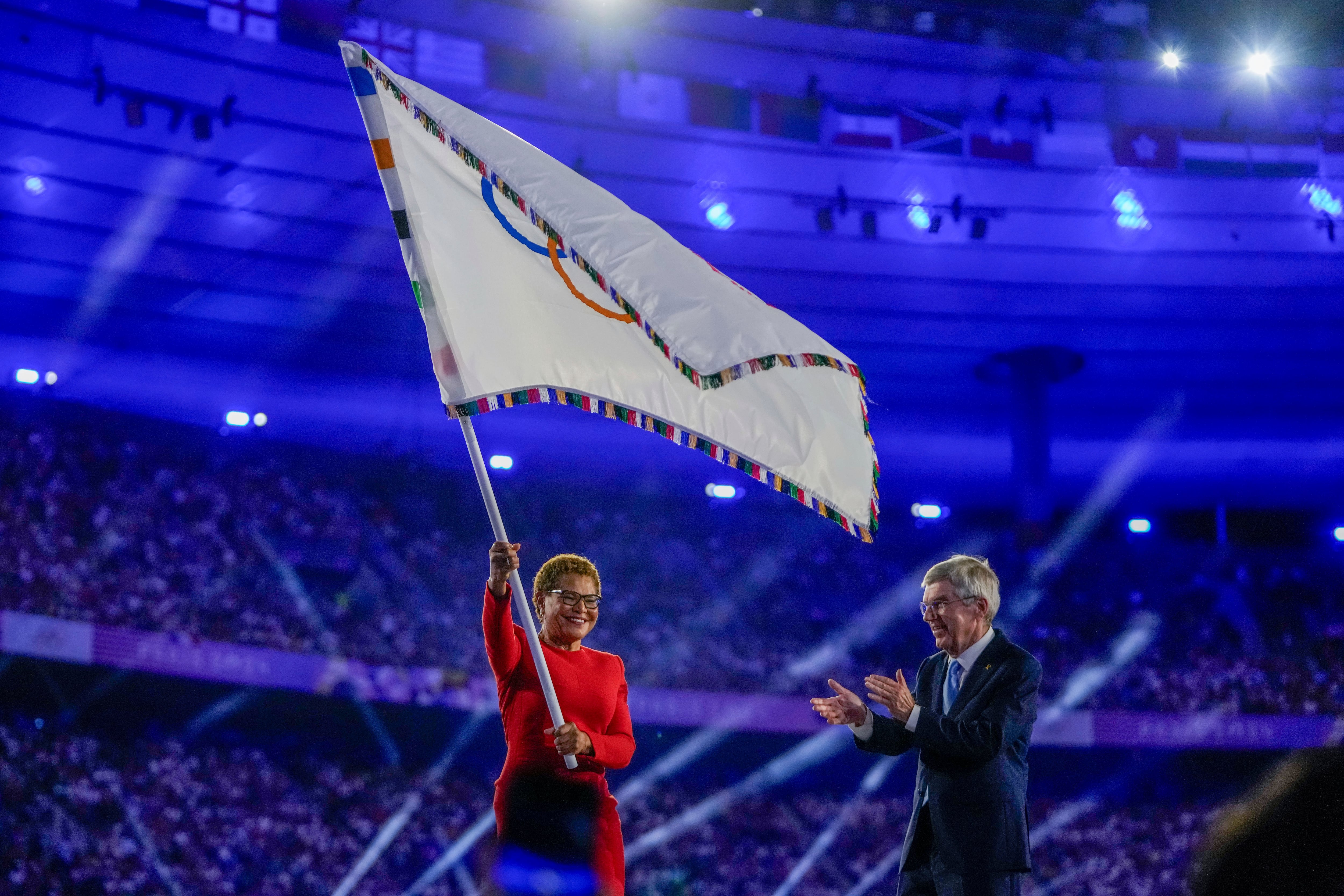 Los Angeles Mayor Karen Bass waves the Olympic flat as IOC President Thomas Bach applauds during the 2024 Summer Olympics closing ceremony at the Stade de France, Sunday in Saint-Denis, France.