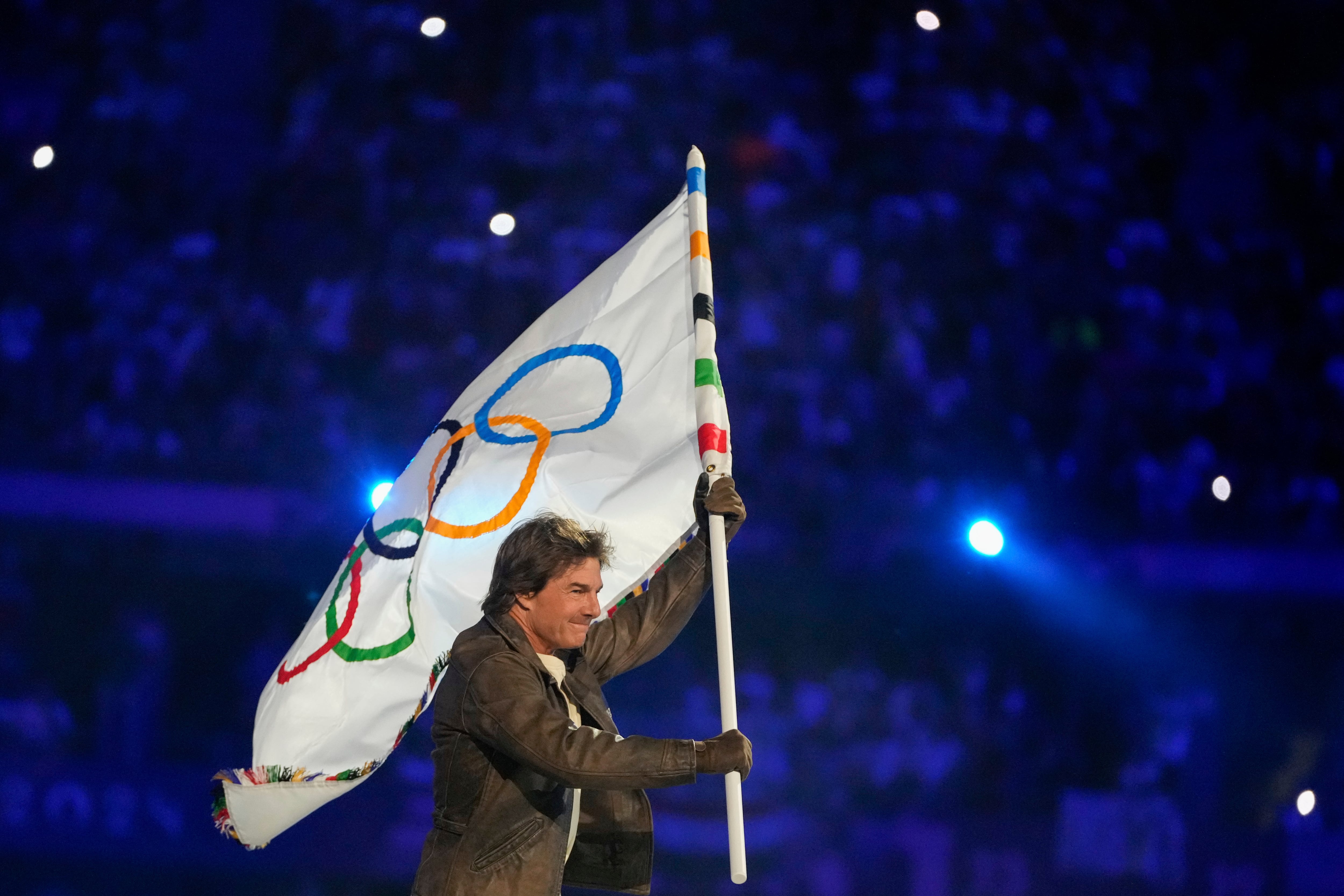 Tom Cruise carries the Olympic flag during the 2024 Summer Olympics closing ceremony at the Stade de France, Sunday in Saint-Denis, France.