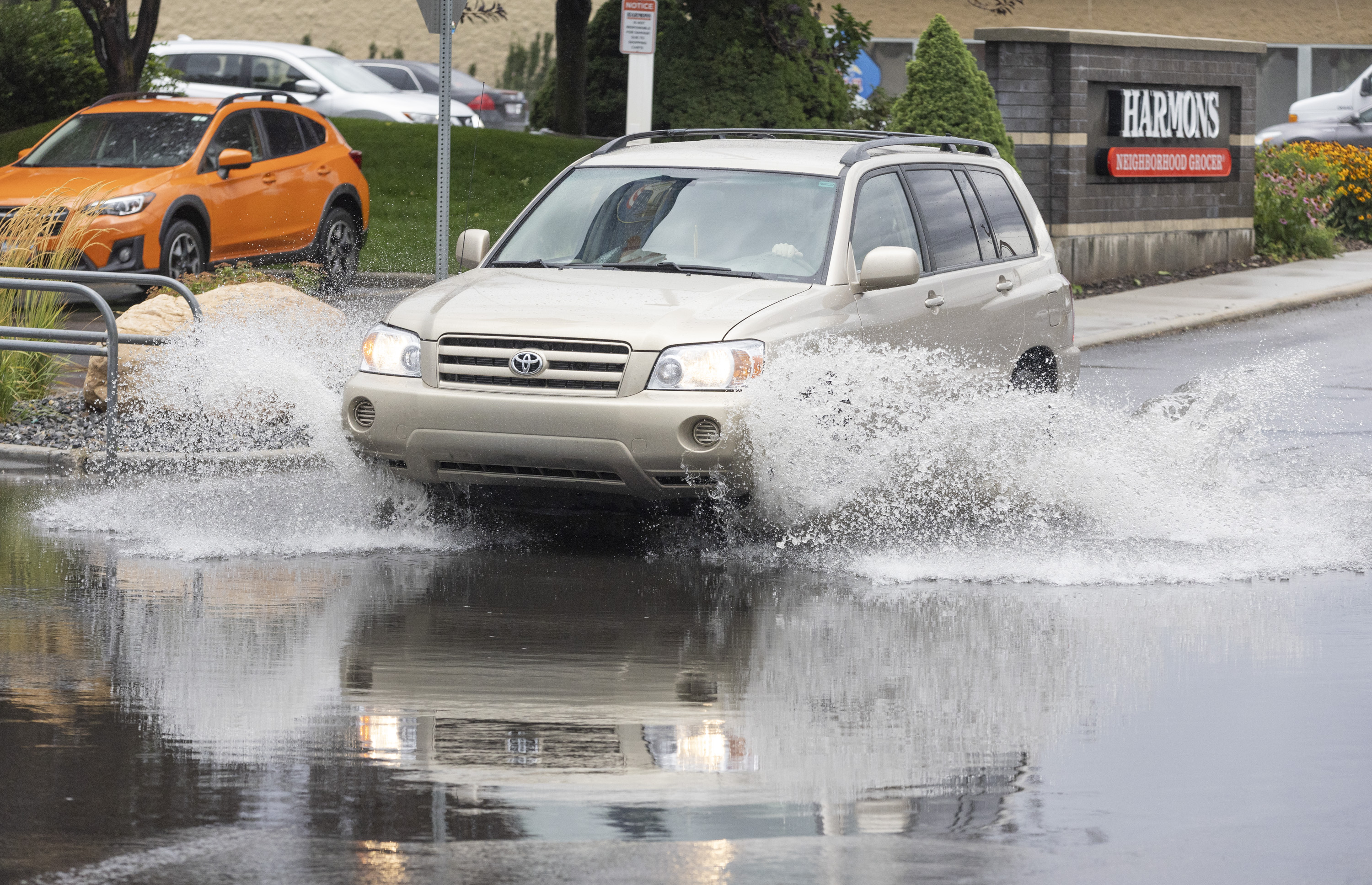 A car drives through a flooded portion of a parking lot after a rain storm in Sandy on Monday.