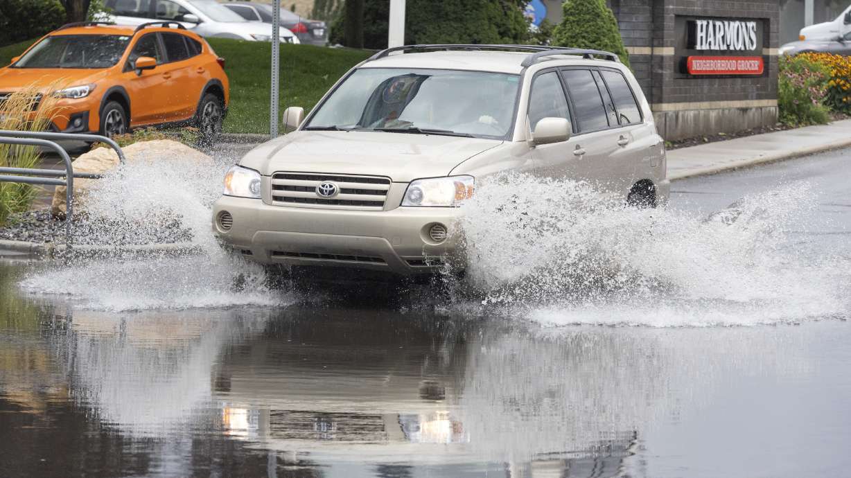 A car drives through a flooded portion of a parking lot after a rain storm in Sandy on Monday.